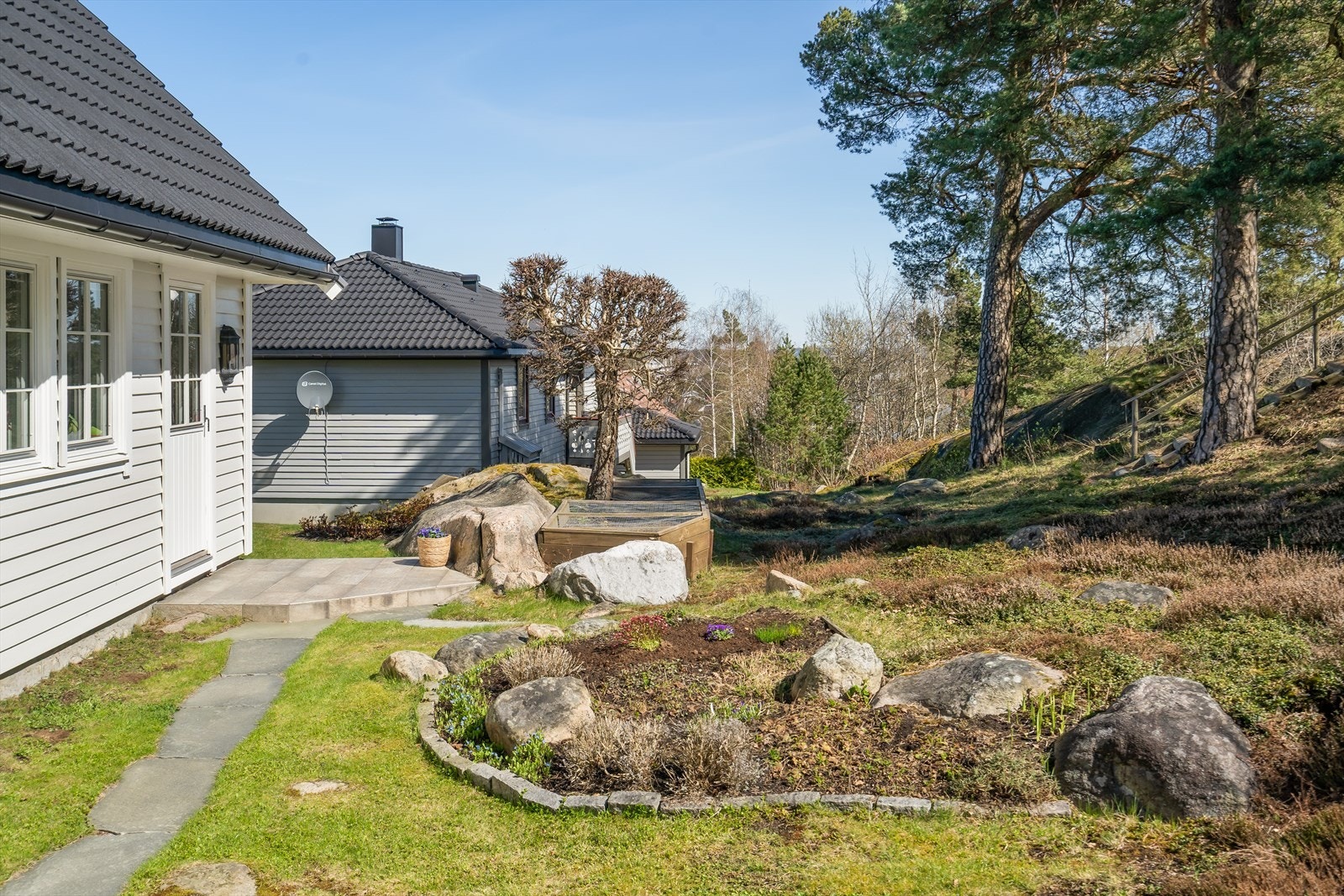 Boligens uteareal er pent opparbeidet med gress, stein og naturlig beplantning. Galleribilde