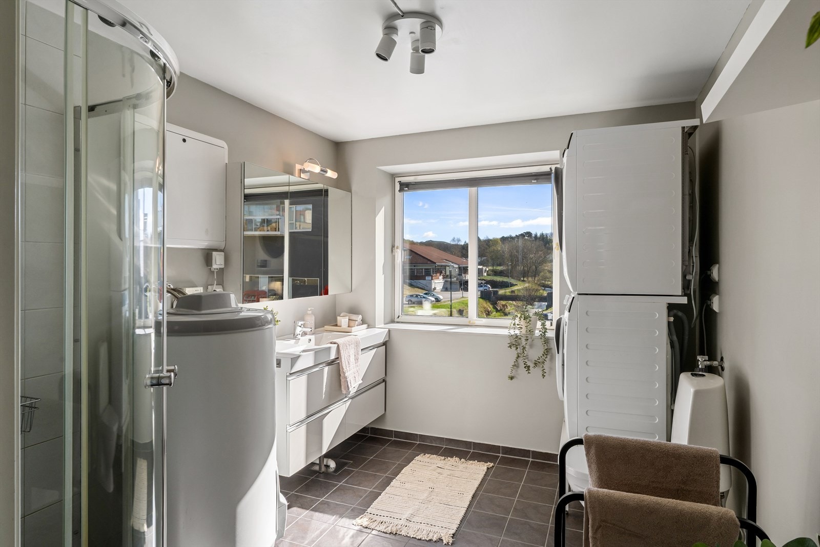 Badet fremstår som romslig med baderomsinnredning i hvit utførelse. Opplegg for vaskemaskin og tørketrommel kan også nevnes. Galleribilde