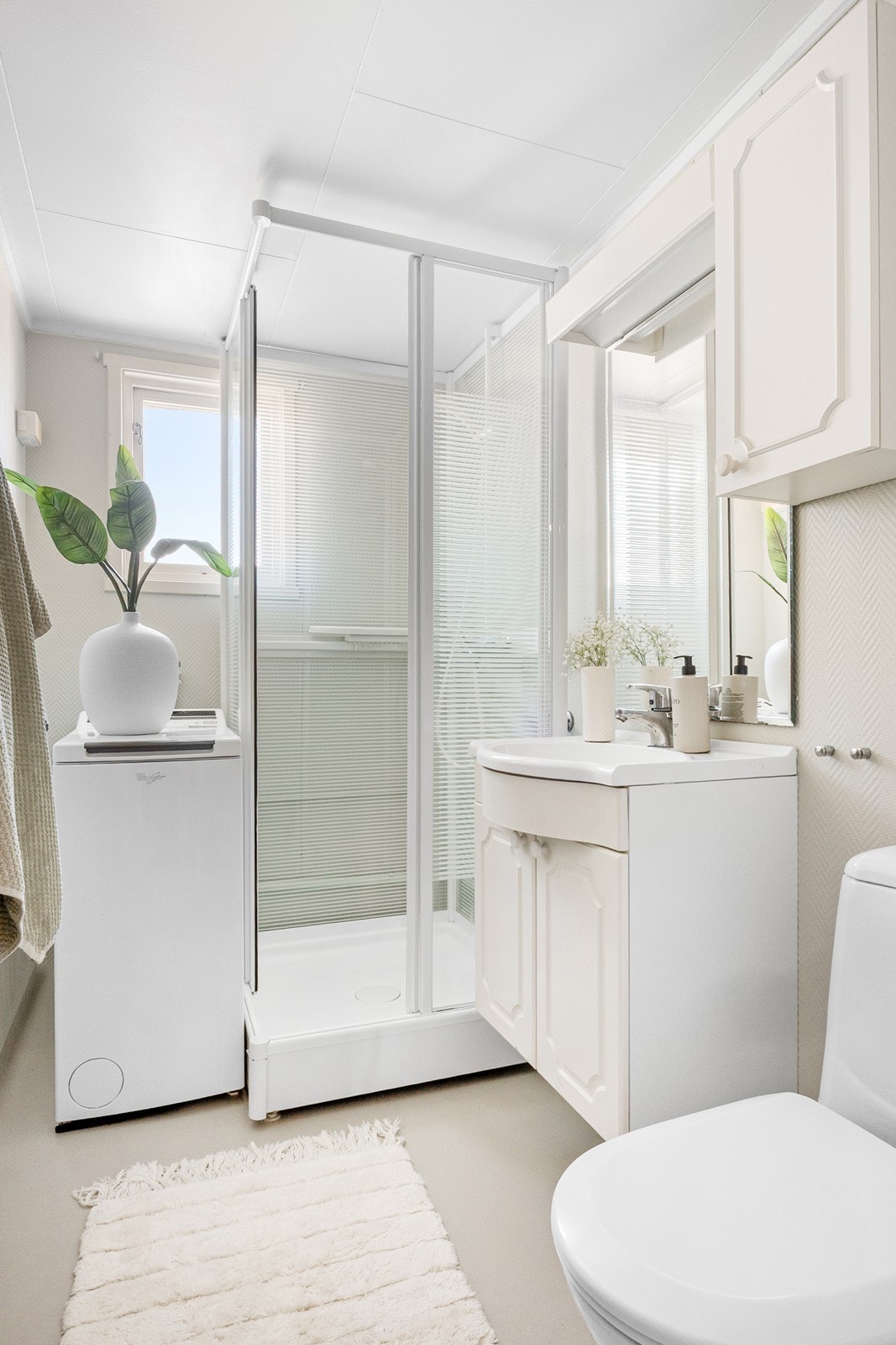 Badet fremstår lyst med enkel innredning og røropplegg for vaskemaskin som kan medfølge. Rommet må oppgraderes for å tåle dagens krav. Galleribilde