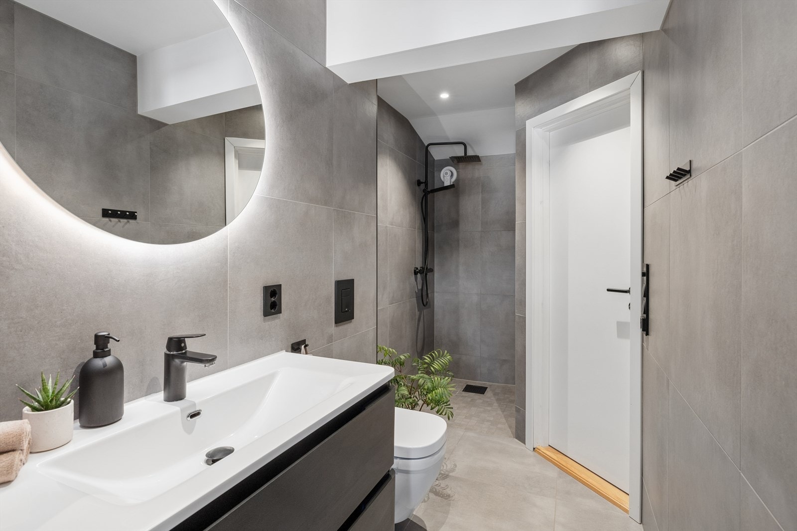 Badet er utstyrt med vegghengt toalett, servantinnredning med praktiske skuffer, speil med integrert belysning og en romslig dusjnisje. Galleribilde