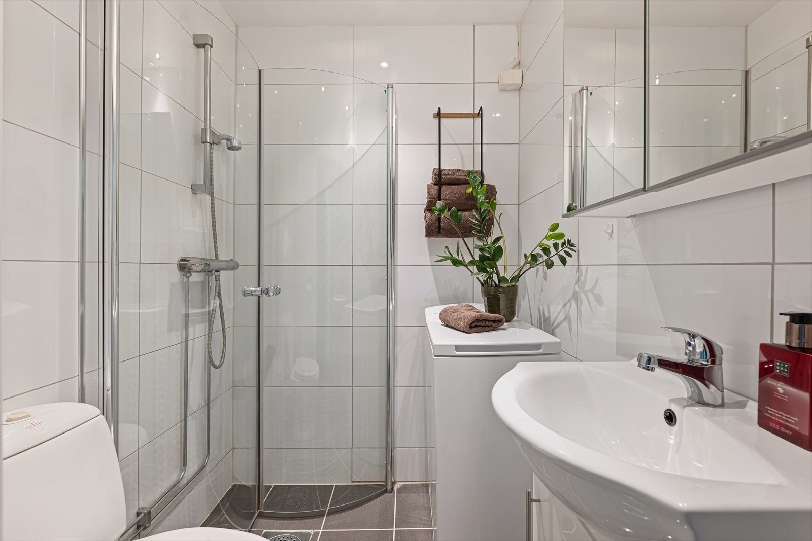 Badet er utstyrt med servant med underskap, speilskap, toalett, dusjhjørne med svingbare glassdører, samt opplegg for vaskemaskin. Galleribilde