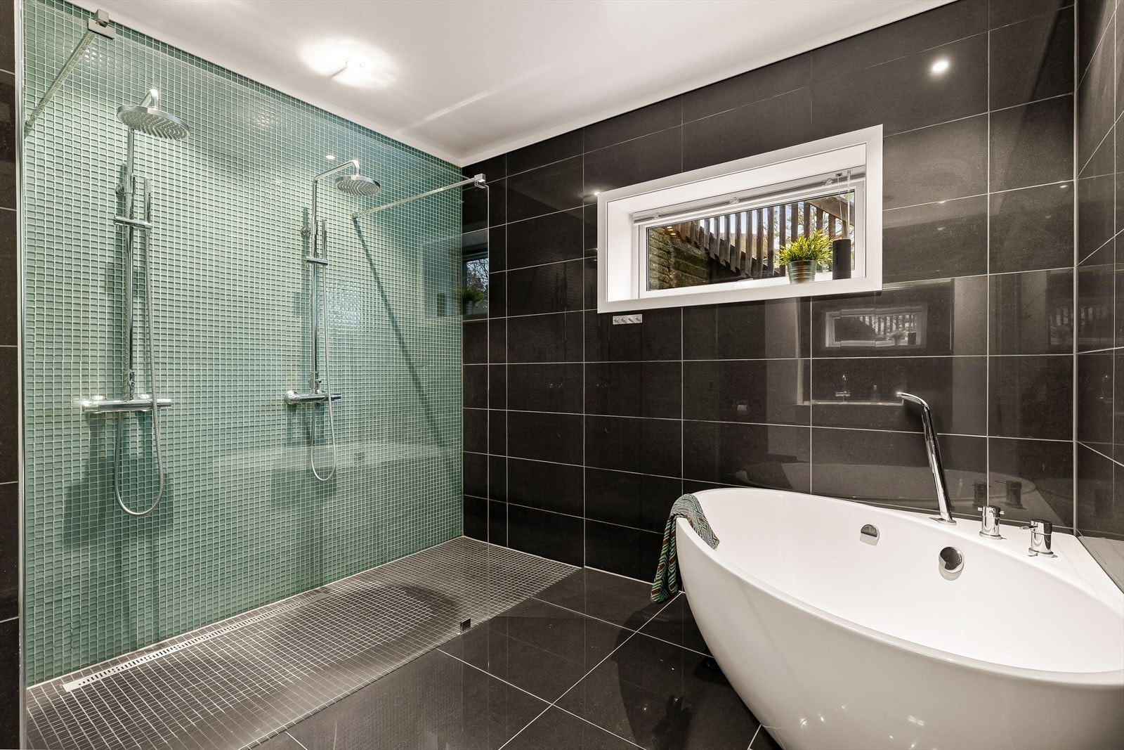 Badet byr på et innbydende badekar som legger til rette for avslappende stunder, samt en romslig dusjnisje som gir en eksklusiv og luksuriøs spa-følelse i hverdagen. Her er alt tilrettelagt for komfort og velvære, i omgivelser som innbyr til ro og nytelse Galleribilde