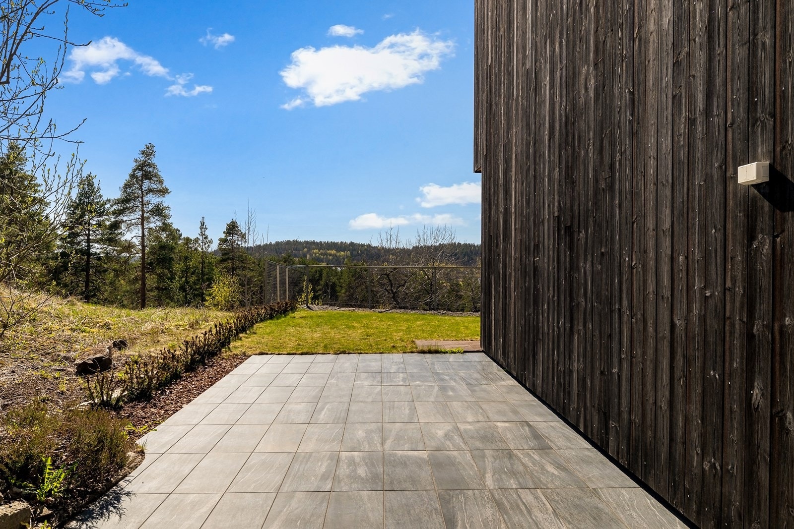 Fra underetasjen er det utgang til en stor, tiltalende markterrasse utført i støpt betong med flislagte overflater. Dette gir et moderne og vedlikeholdsvennlig uterom med god plass til både sittegrupper og øvrig møblement . Galleribilde