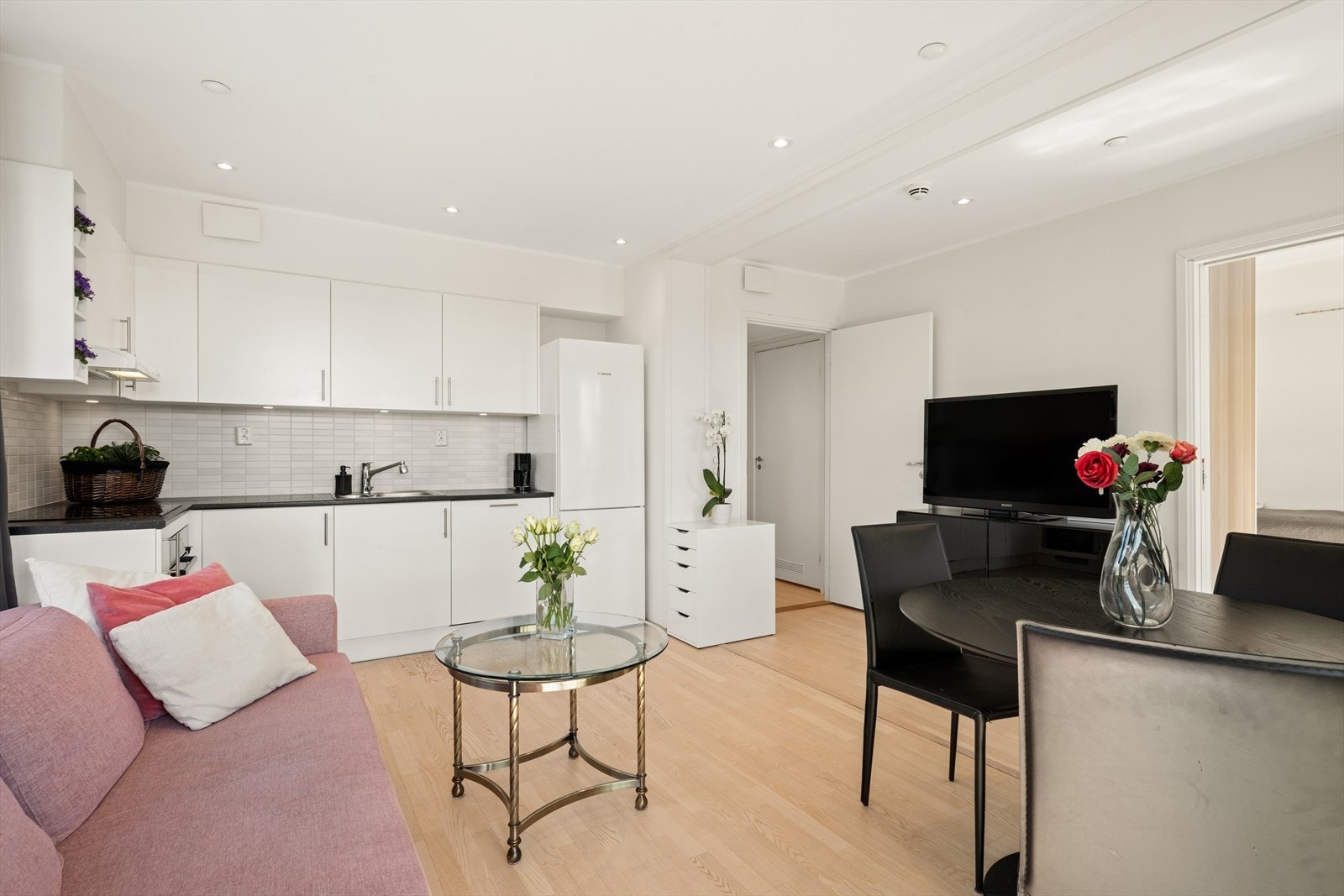 Tidløst kjøkken med hvite, glatte fronter og delikate fliser over benker. Legg merke til downlights i taket som er gjennomgående i alle rom. Galleribilde
