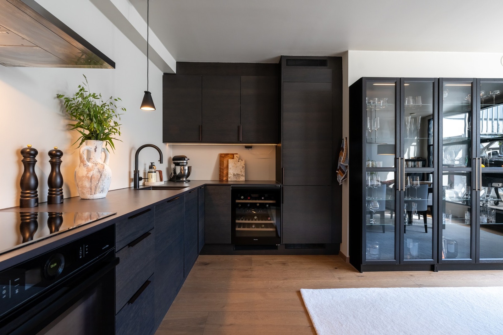 Mørk innredning med finerte fronter, Dekton benkeplate og underlimt oppvaskkum i sort utførelse og Quooker for kokende vann fra springen. Galleribilde