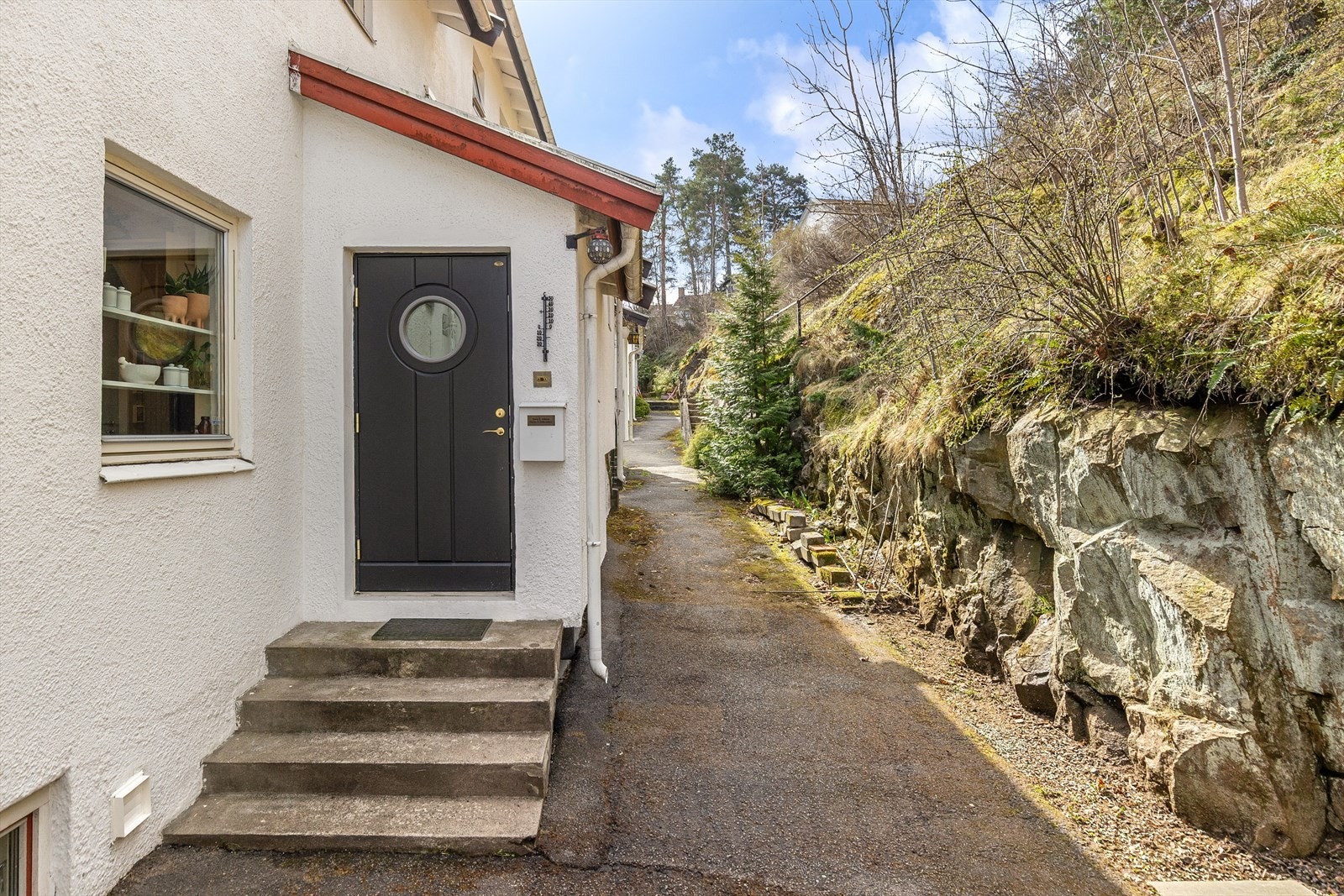 Inngangsparti på baksiden av huset. Eiet tomt som går videre opp i terrenget bak boligen. Galleribilde
