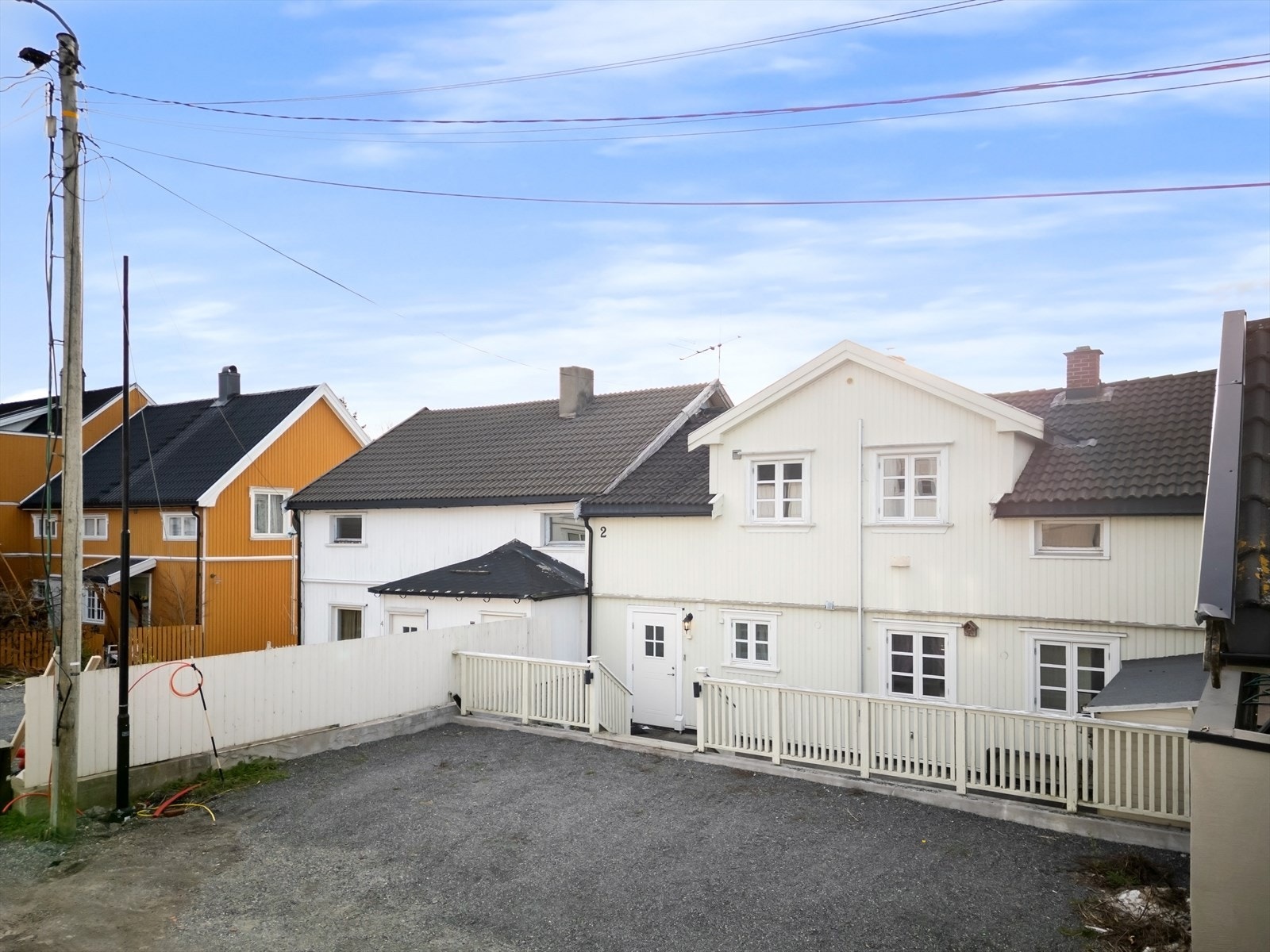 Eiendommen har en praktisk, gruset gårdsplass for parkering. Med to separate enheter åpner boligen for fleksible løsninger som utleie eller generasjonsbolig. Galleribilde