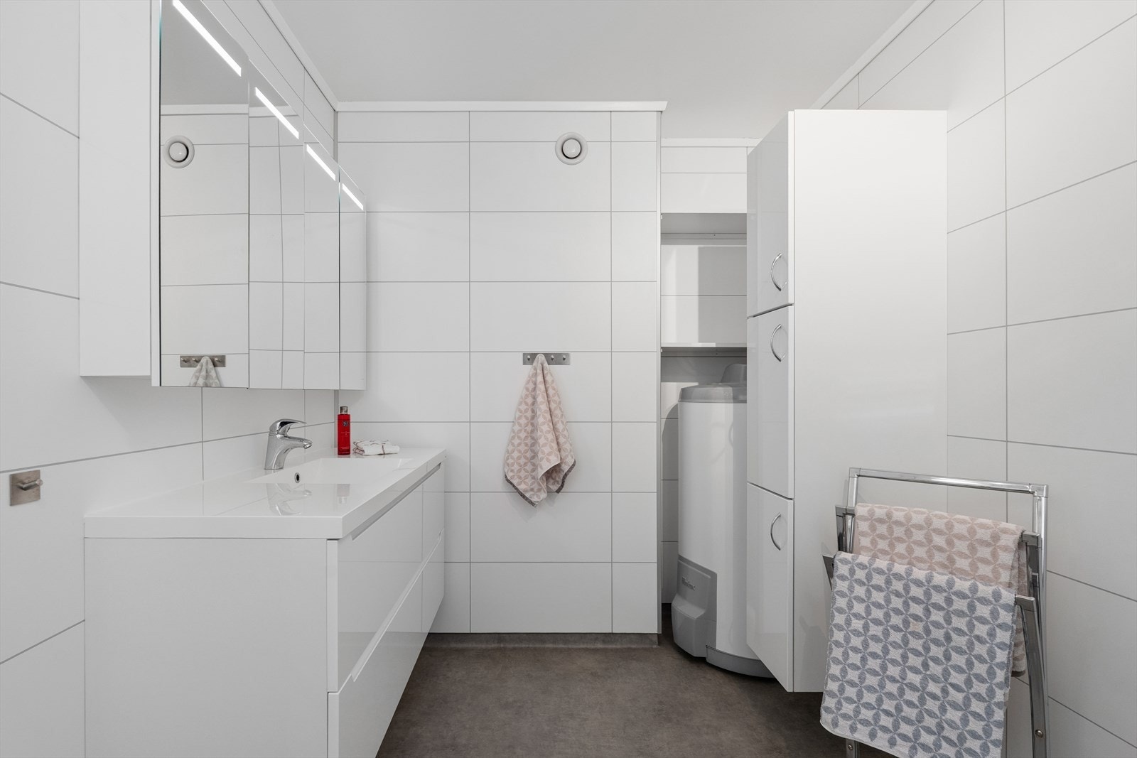 Badet er innredet med en bred servant med skuffer, speilskap med belysning og vegghengt oppbevaring. Galleribilde