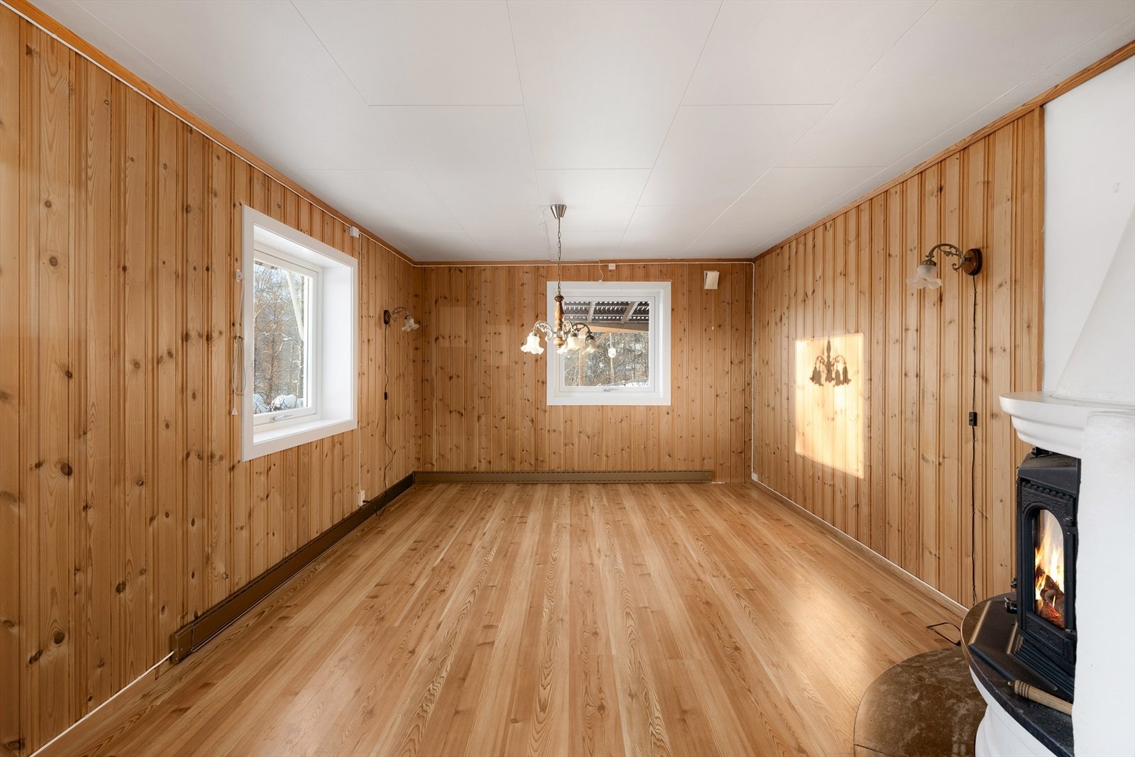 Stuen har vegger med trepanel og takessplater i lyse farger. Galleribilde
