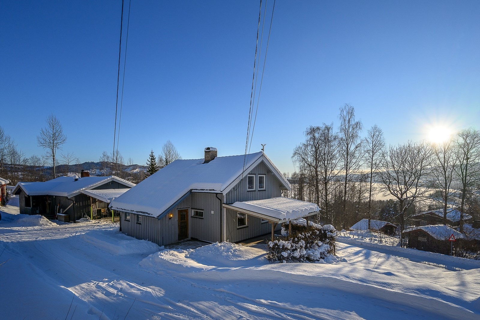 Eneboligen ligger i et lett skrånet terreng med en opparbeidet tomt med plen og grusareal. Galleribilde