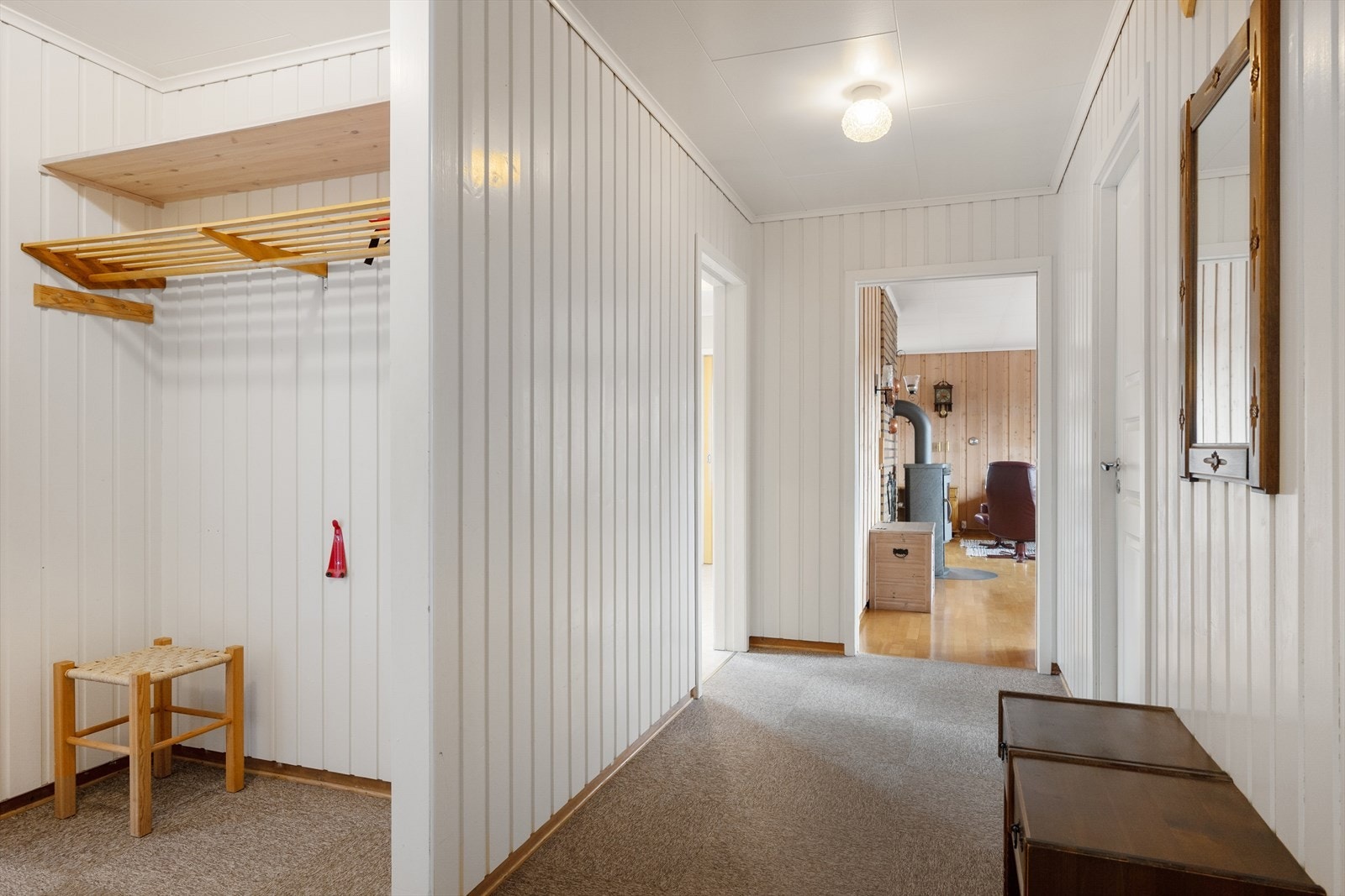 Entréen har vegger med trepanel og teppefliser på gulvet, og leder videre inn til boligens øvrige rom. Galleribilde