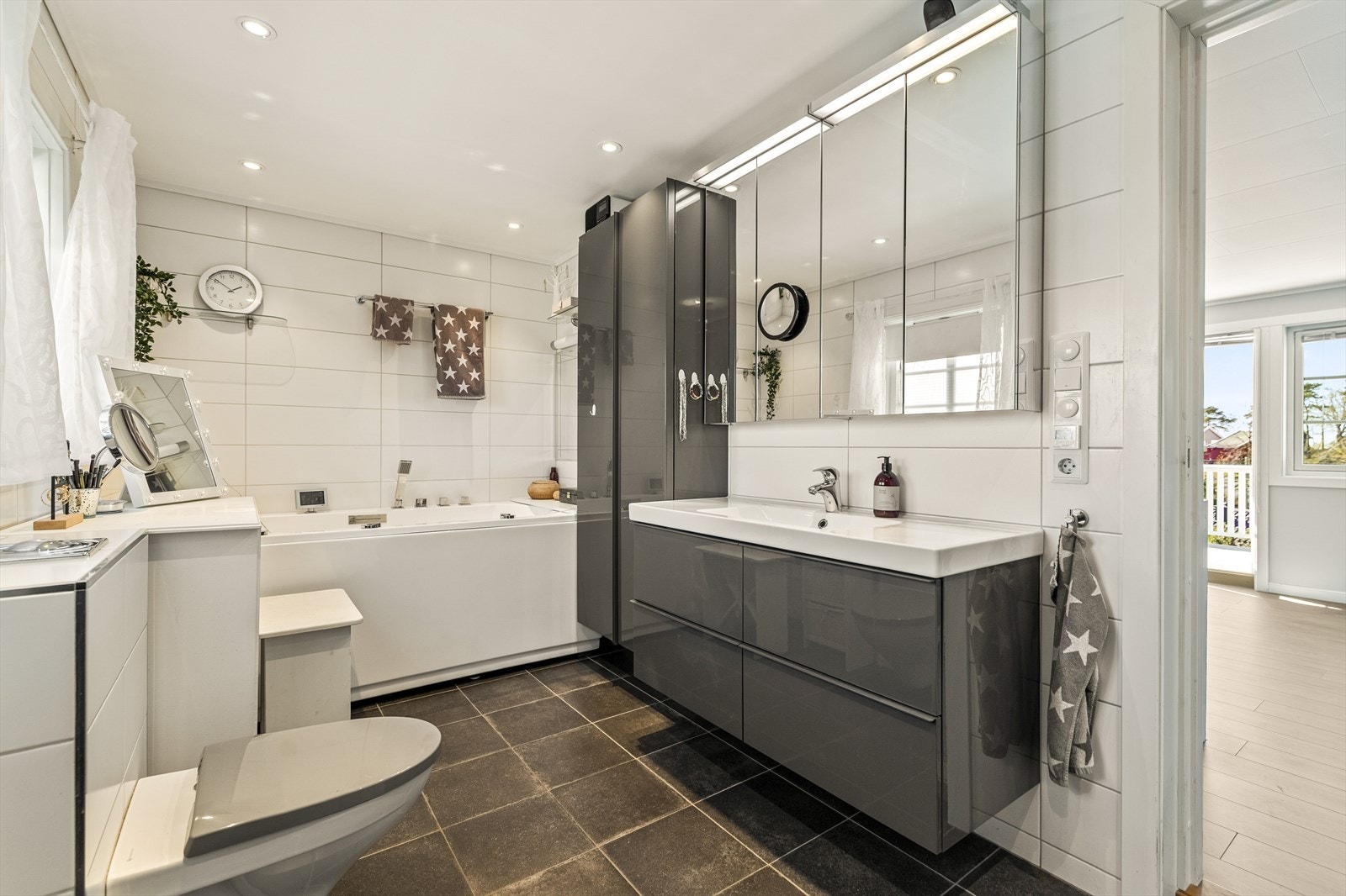 Badet er flislagt på gulv og vegger, med varmekabler i gulv, og innredet med vegghengt toalett, dusj og servantinnredning. Galleribilde