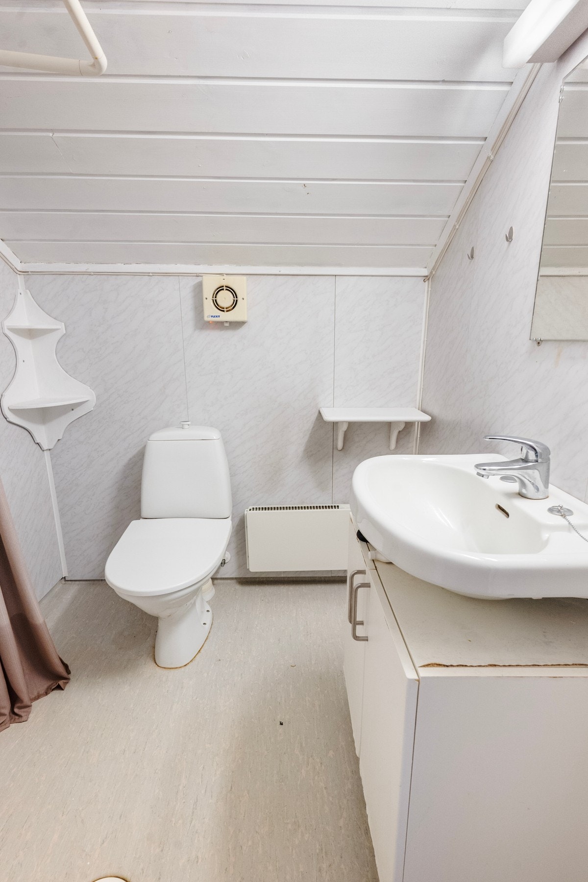 Badet har belegg på gulv og våtromsplater på veggene. Badet er innredet med servant med underskap, dusj med forheng og gulvmontert toalett. Oppvarming via panelovn. Galleribilde