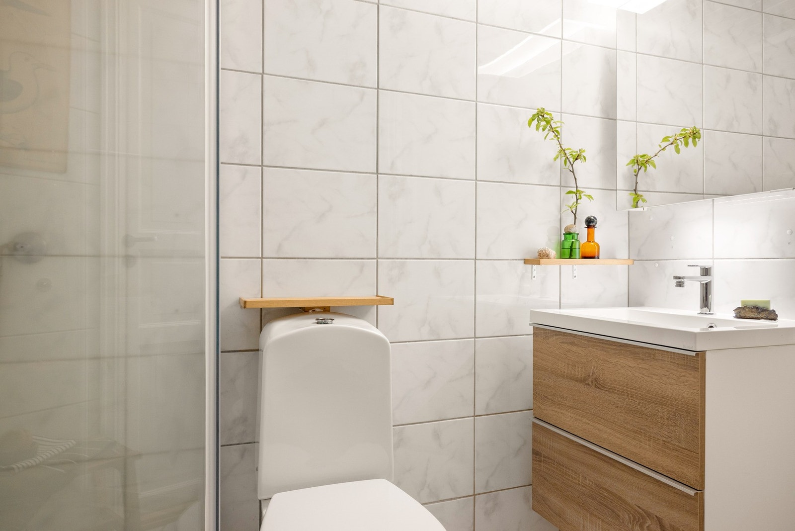 Badet er innredet med toalett, dusjkabinett, og baderomsmøblement med speil og belysning. Galleribilde