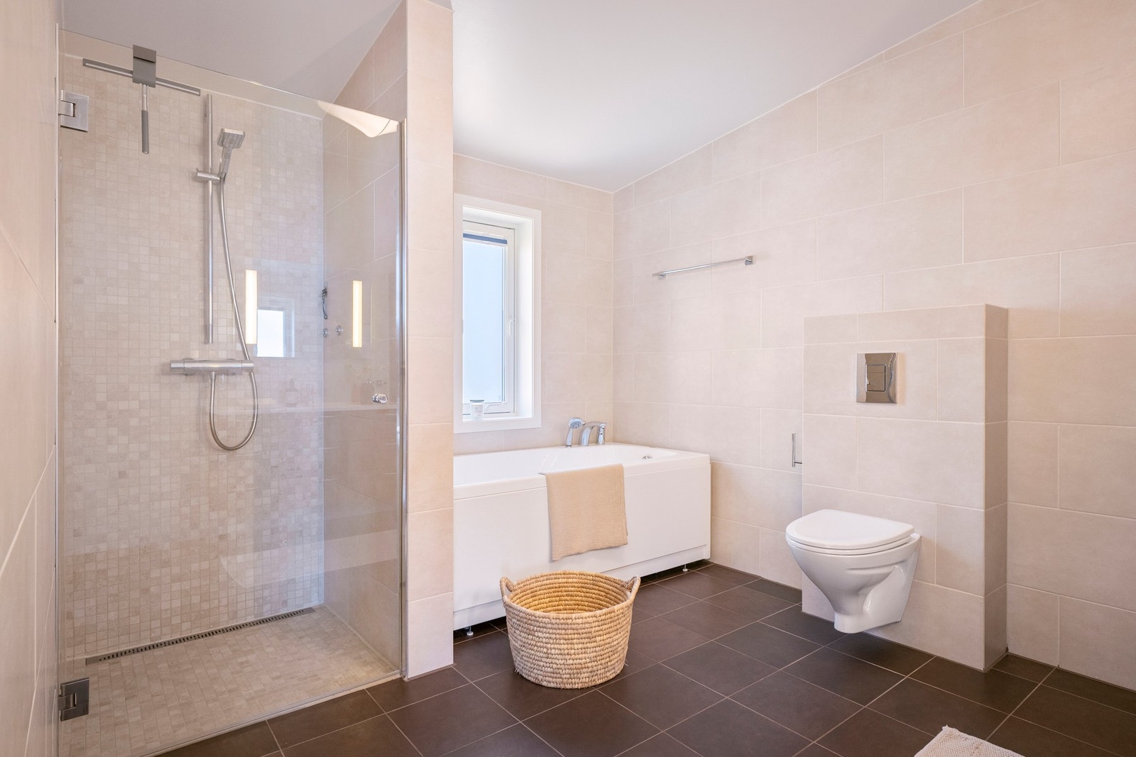 Badet i 2. etasje er flislagt og fremstår som lyst og velholdt med et tidløst uttrykk. Her er det dusjløsning, servant med innredning og vegghengt toalett Galleribilde