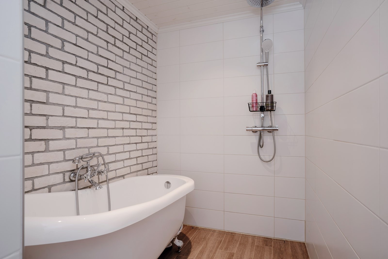 Badet er innredet med dobbel servant, gulvstående toalett, badekar og dusjhjørne. Galleribilde