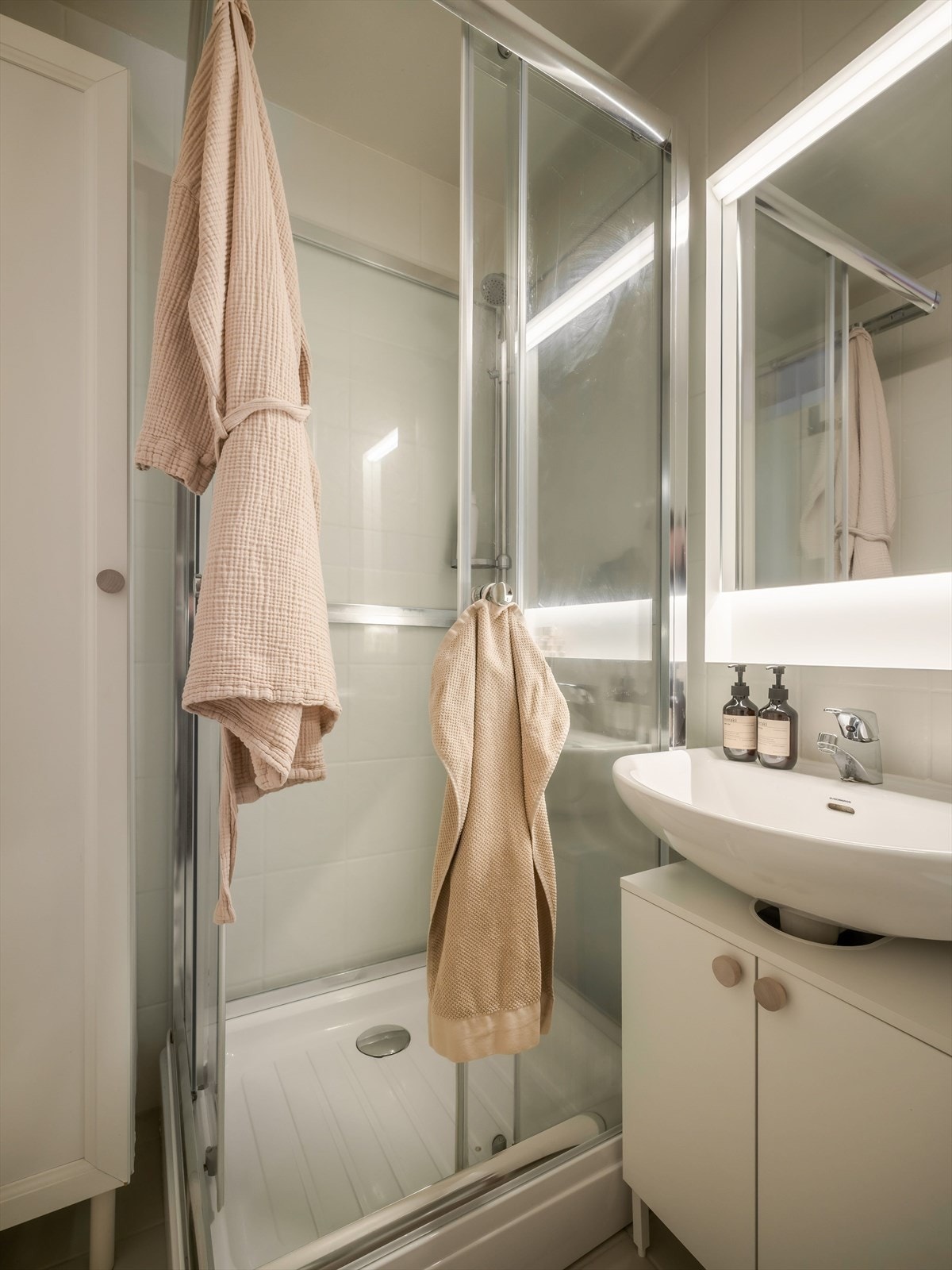 Badet er utstyrt med servant, speil, skap, belysning, høyskap, dusjkabinett og toalett. Galleribilde