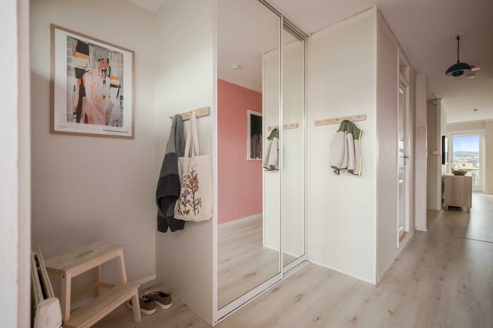 Den lyse gangen har god plass til å sette ifra seg sko og henge opp ytterklær samt god plass til oppbevaring i en romslig skyvedørsgarderobe med speilfronter. Galleribilde