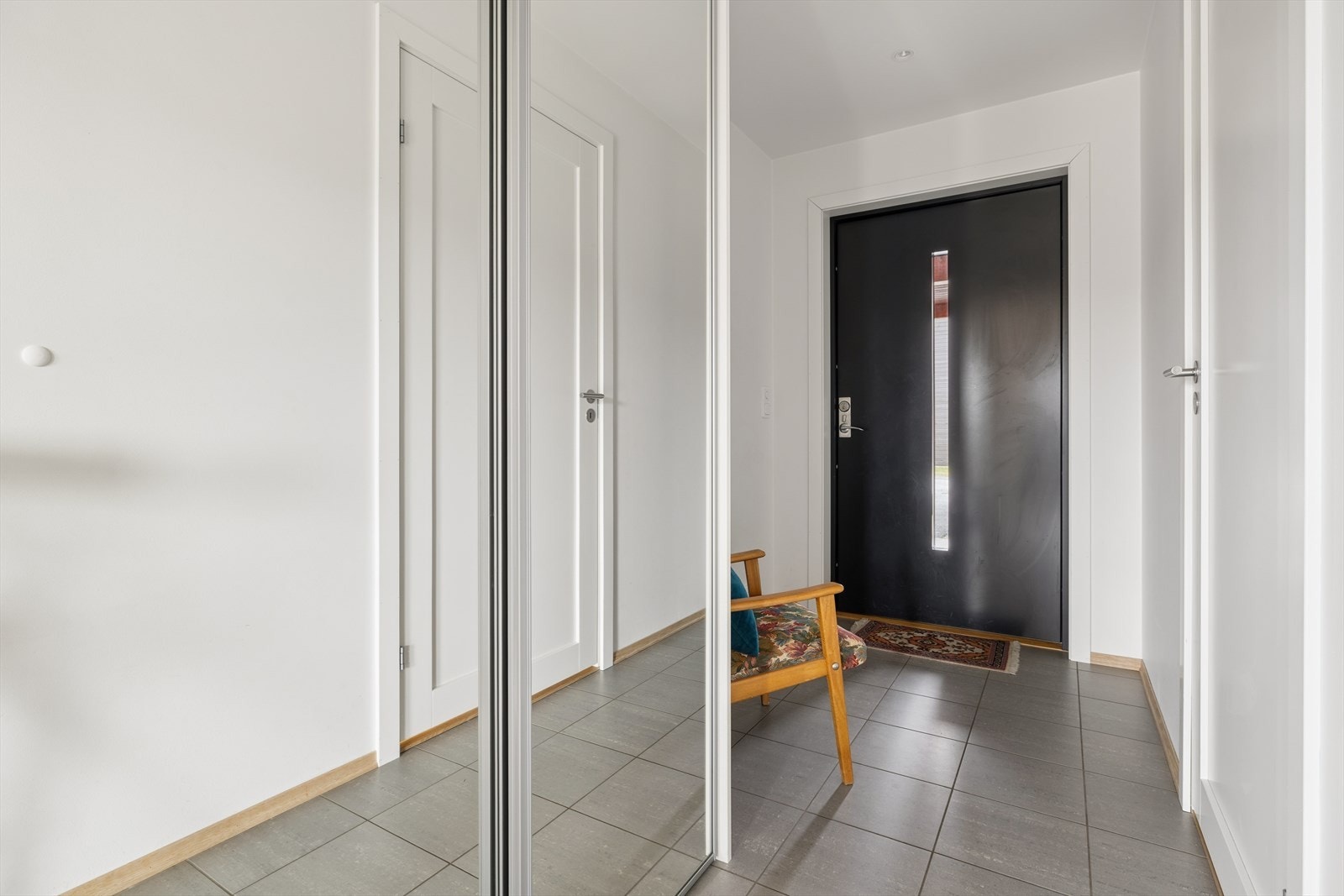 Romslig entré med flislagt gulv og gode oppbevaringsmuligheter i skyvedørsgarderobe. Galleribilde