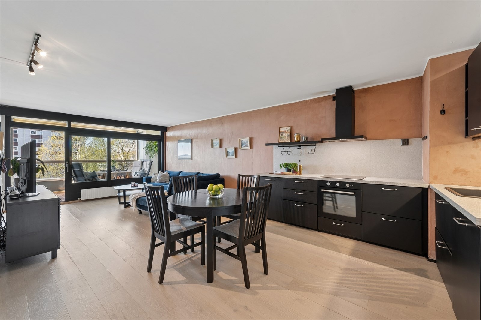 Et helhetlig blikk på det sosiale allrommet, hvor stue, spisestue og kjøkken er samlet. Galleribilde