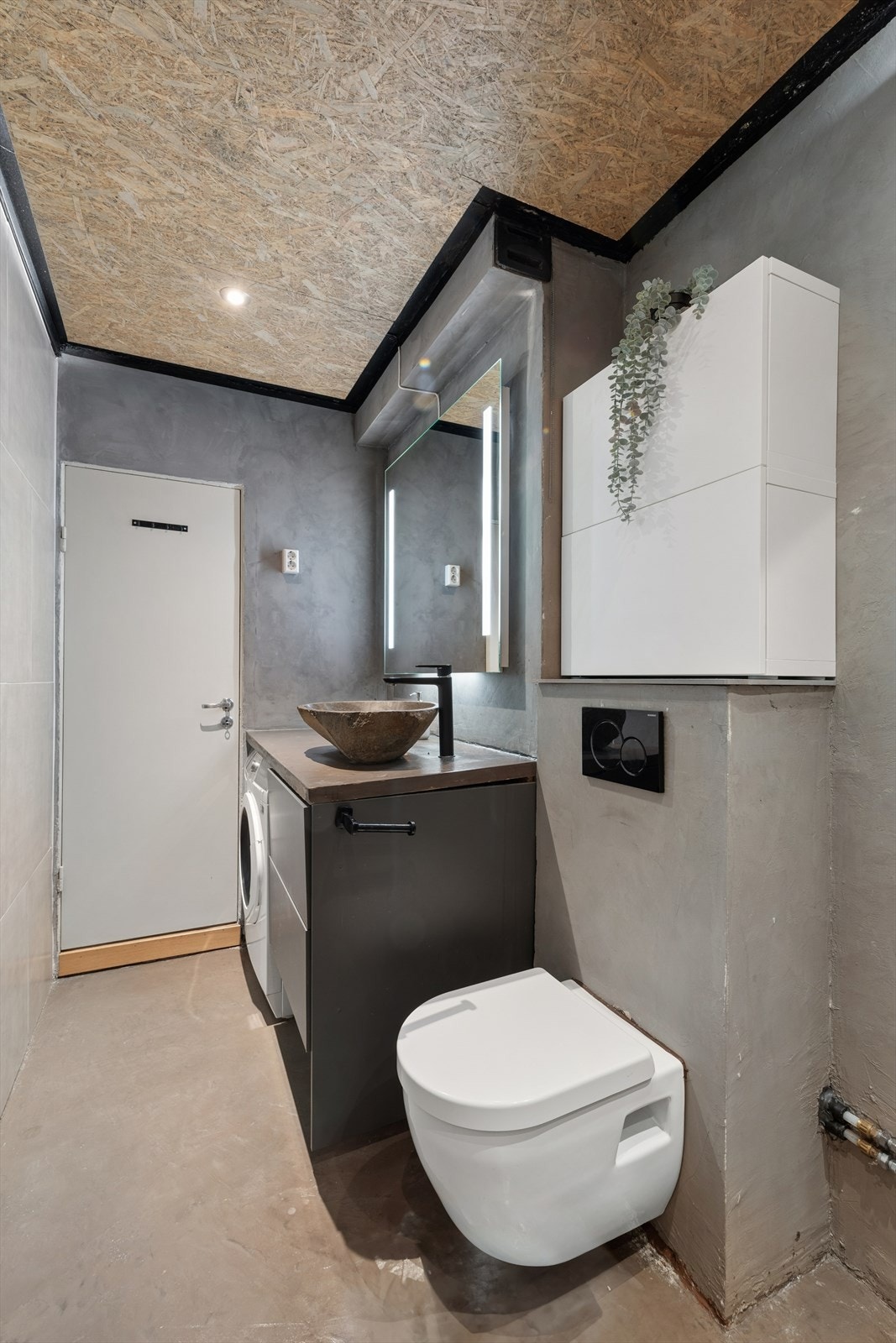 Badet er utstyrt med vegghengt toalett, dusjhjørne med glassvegger og opplegg for vaskemaskin. Galleribilde