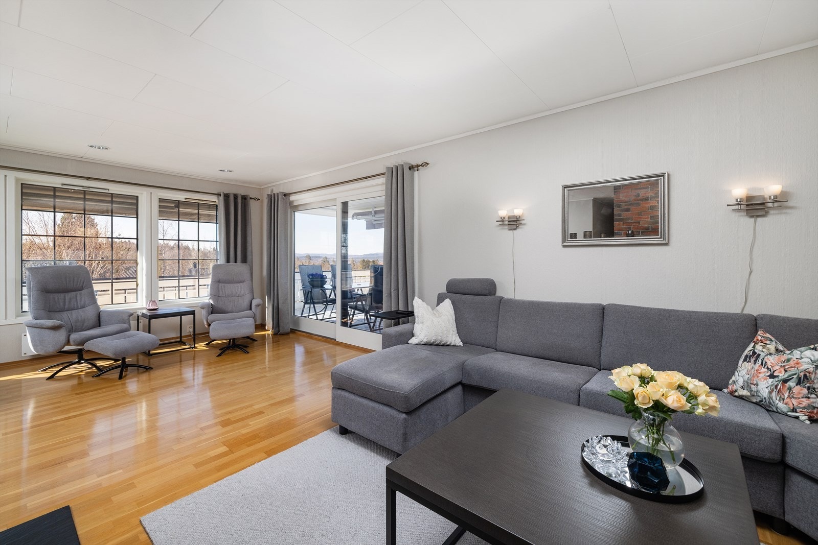 Stuen har downlightsbelysning, store vinduer og skyvedør i glass ut til verandaen. Galleribilde