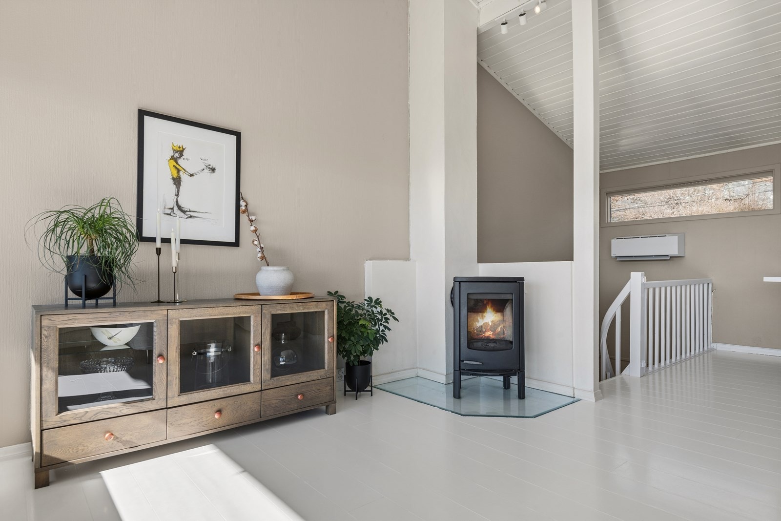 Stuen har en stemningsfull vedovn, supplert av en energieffektiv luft-til-luft varmepumpe installert i 2022 for jevn temperatur året rundt. Galleribilde