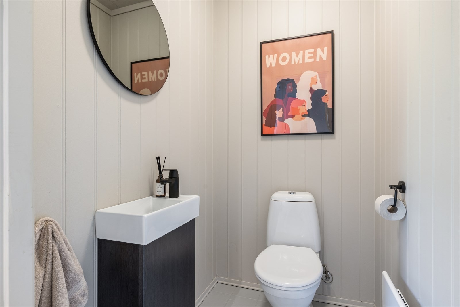 Toalettrom med toalett og servantskap. Fliser på gulv og mdf-plater på vegg. Galleribilde