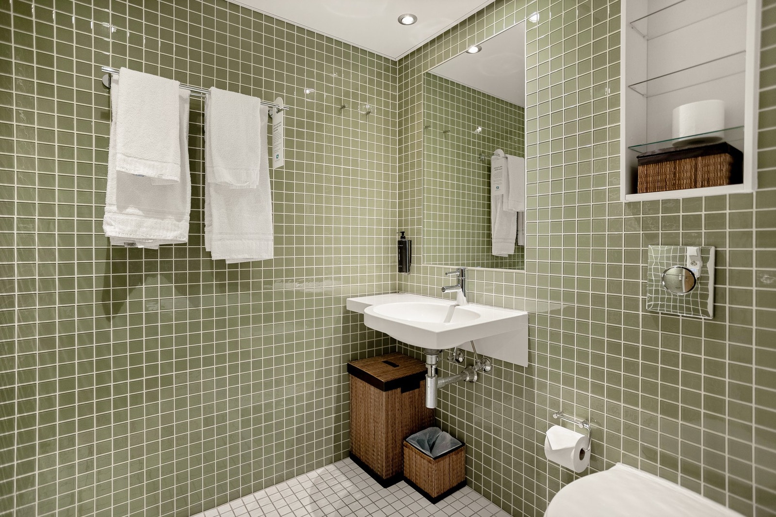Hovedbadet har lyse fliser på gulv med behagelig gulvvarme, flislagte vegger, downlights i himling og praktiske veggnisjer for oppbevaring. Galleribilde