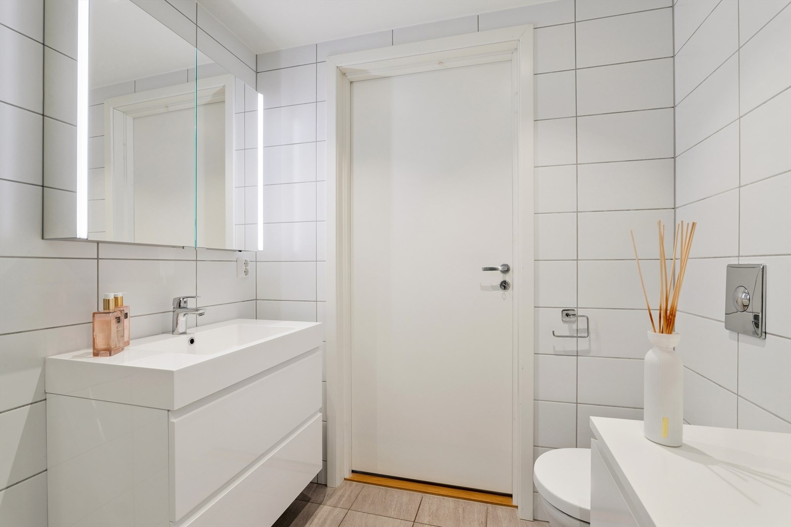 Badet er flislagt og inneholder innredning med nedfelt servant, veggmontert toalett og dusjhjørne Galleribilde