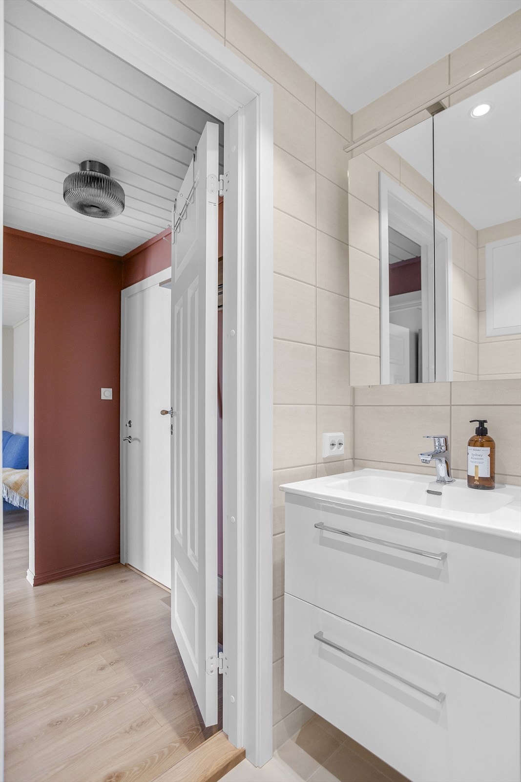 Badet er utstyrt med innredning med servant, speilskap og veggmontert toalett. Galleribilde