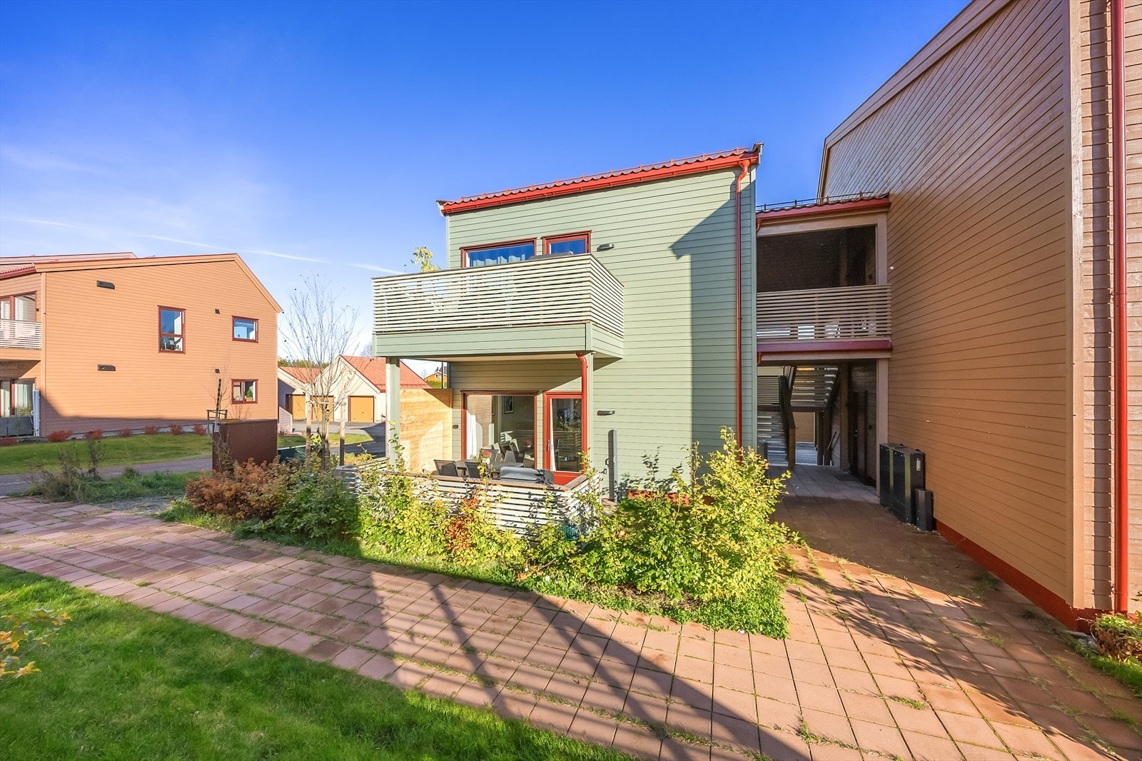 Fasade bakside med terrasse, og hekk på leilighets andel av tomten. Galleribilde