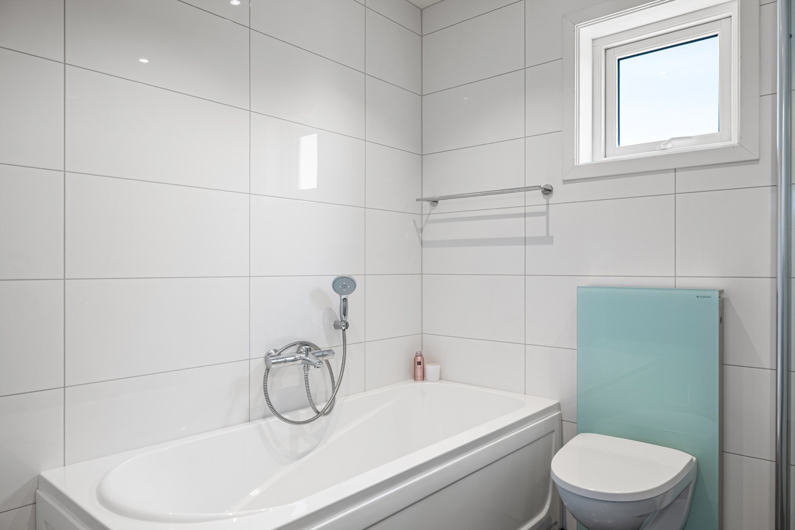 Badet er innredet med nedfelt servant, veggmontert toalett, badekar og dusjvegger/hjørne Galleribilde
