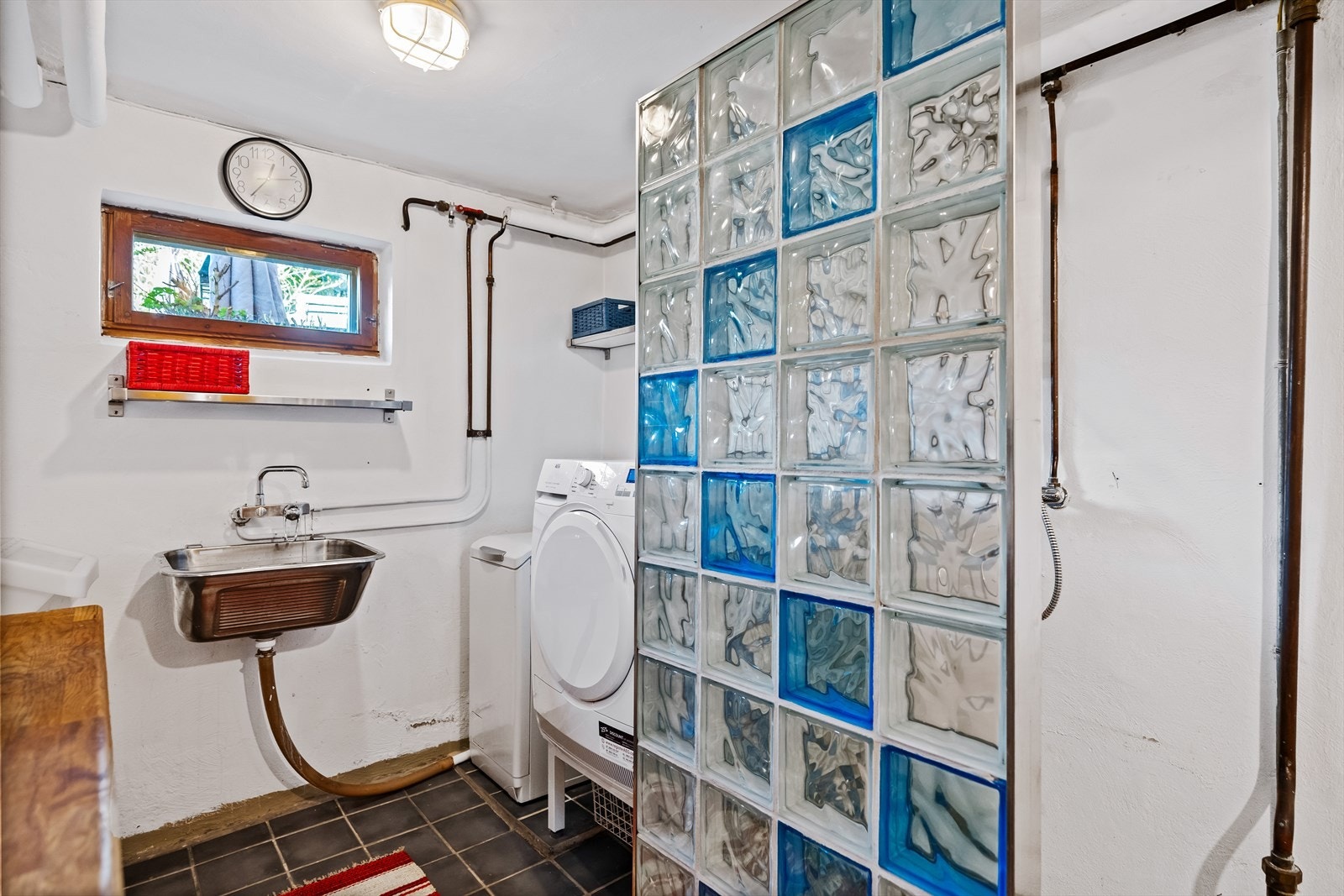 Det er fliser på gulvet, malte og pussede overflater på vegger samt slette overflater i himlingen. Rommet er innredet med utslagsvask, dusj på gulv og opplegg for vaskemaskin. Galleribilde