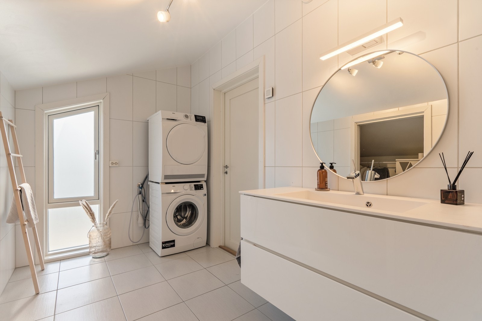 Badet har innredning med nedfelt servant, vegghengt toalett og dusjhjørne med glassvegger, samt opplegg for vaskemaskin Galleribilde
