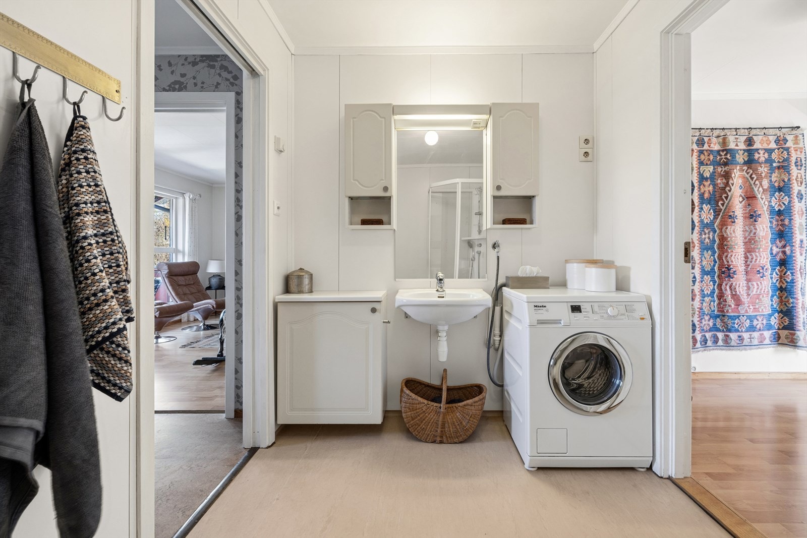 Her er det innredning med profilerte fronter, servant på vegg, speilskap med lysarmatur og opplegg for vaskemaskin. Galleribilde