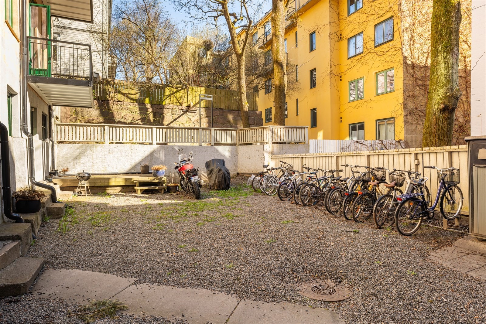 Skjermet bakgård med terrasseplatting med sittegruppe, sykkelstativ og diverse beplantning. Galleribilde