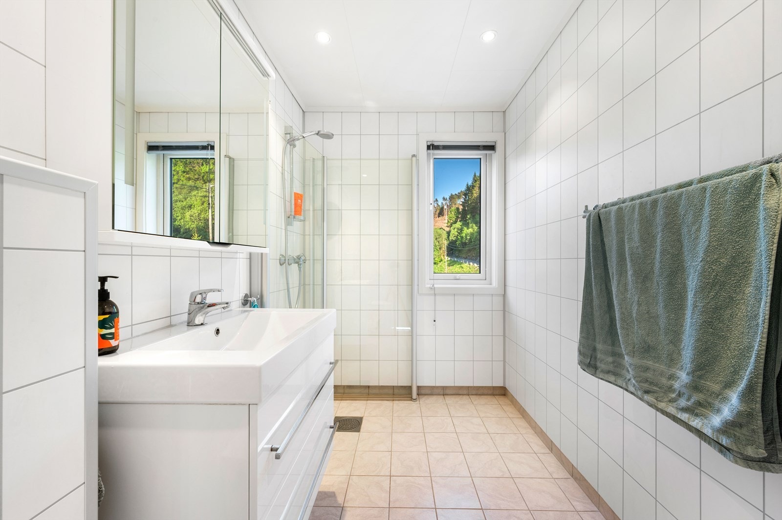 Badet har vegghengt toalett, speilskap og dusjhjørne med innfellbare glassvegger Galleribilde