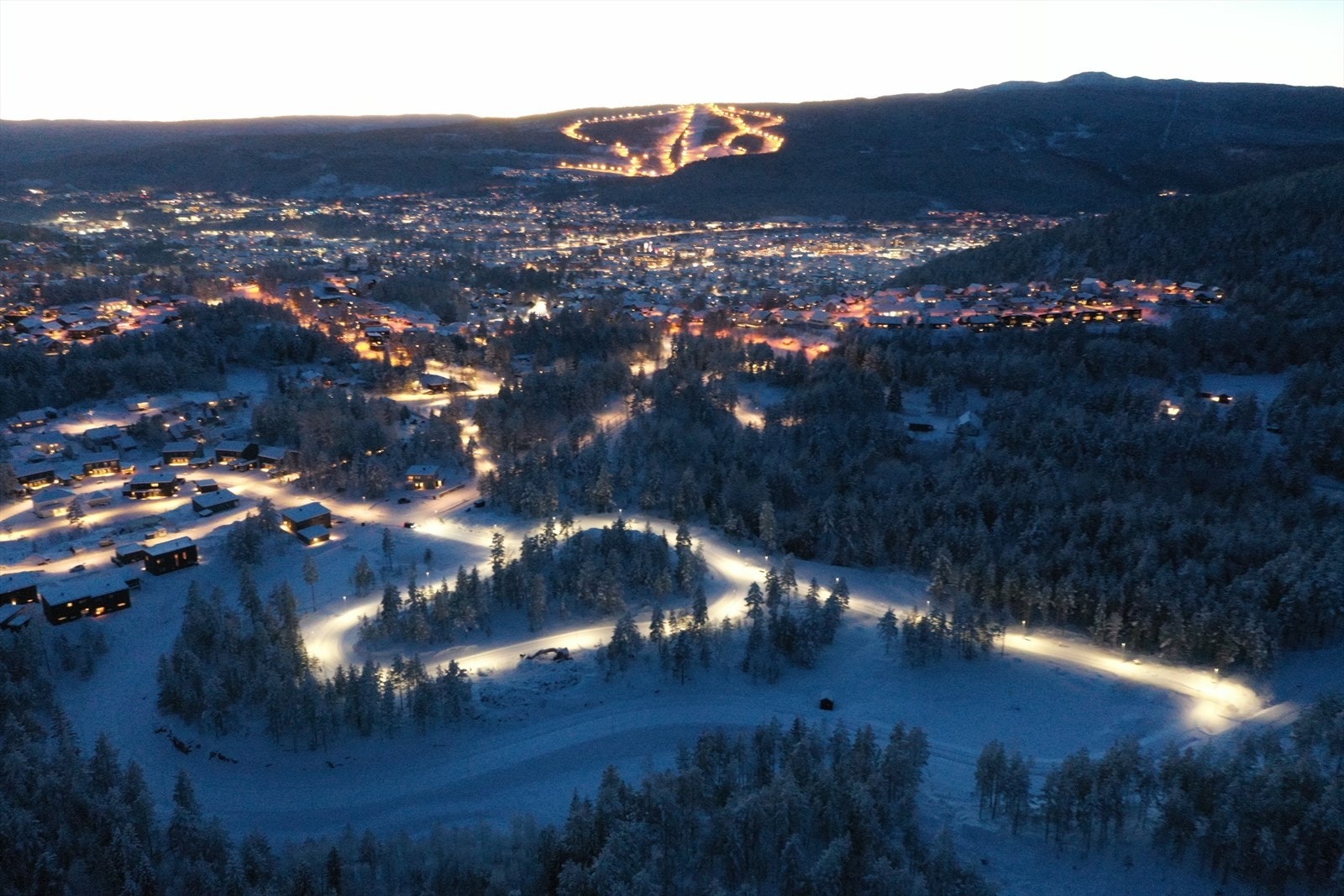 Kveldsbilde av Rødshøgda med byen og skisenteret i bakgrunn. Galleribilde