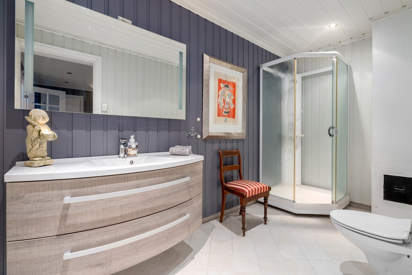 Badet i 1.etasje har flislagt gulv varme og malt panel på vegg. Nyere servantinnredning med servant, speil, toalett og dusjkabinett. Galleribilde