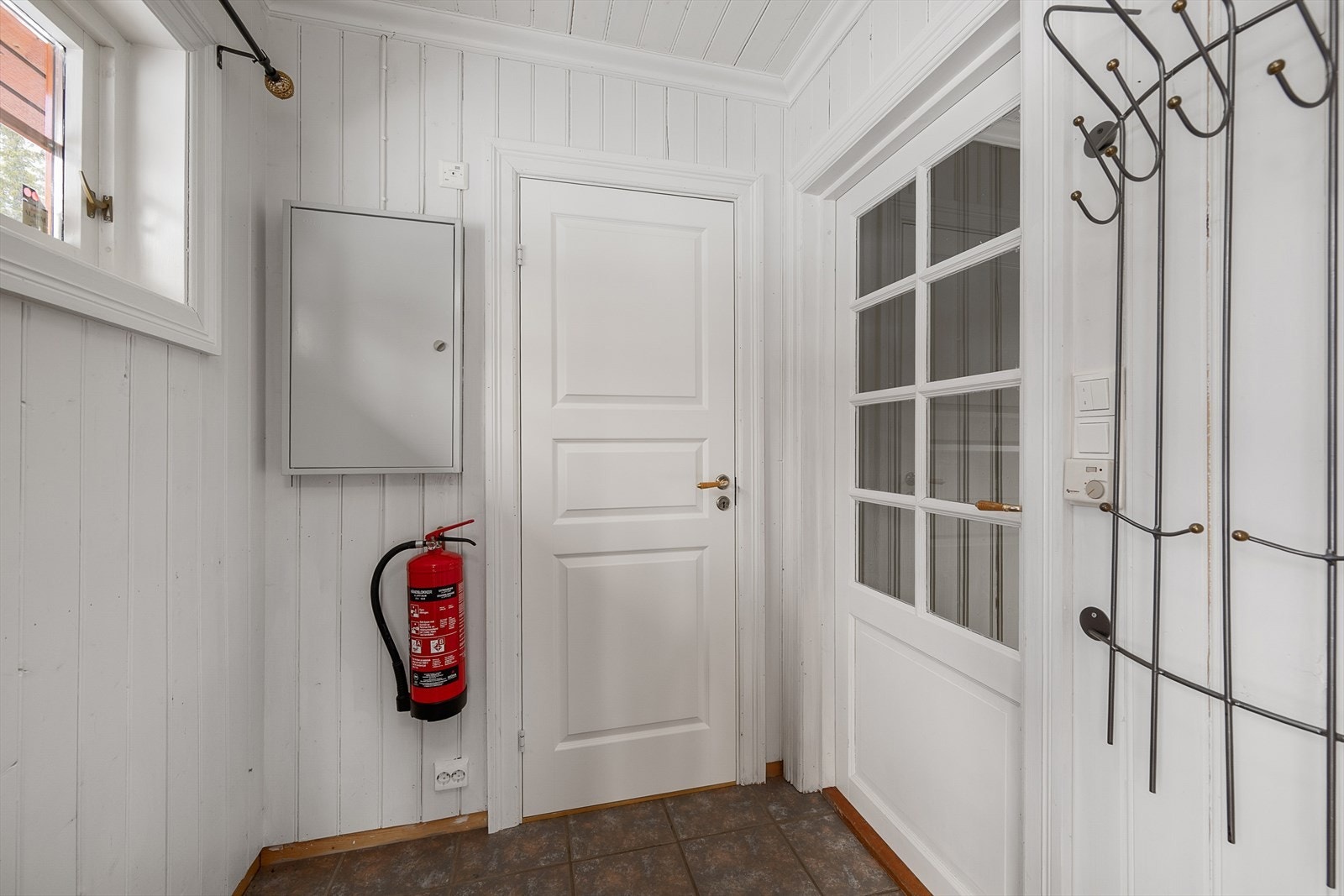 Entréen i hovedhytta har flislagt gulv og dør med glassfelt inn mot gangen. Plass til å henge fra seg yttertøy. Galleribilde