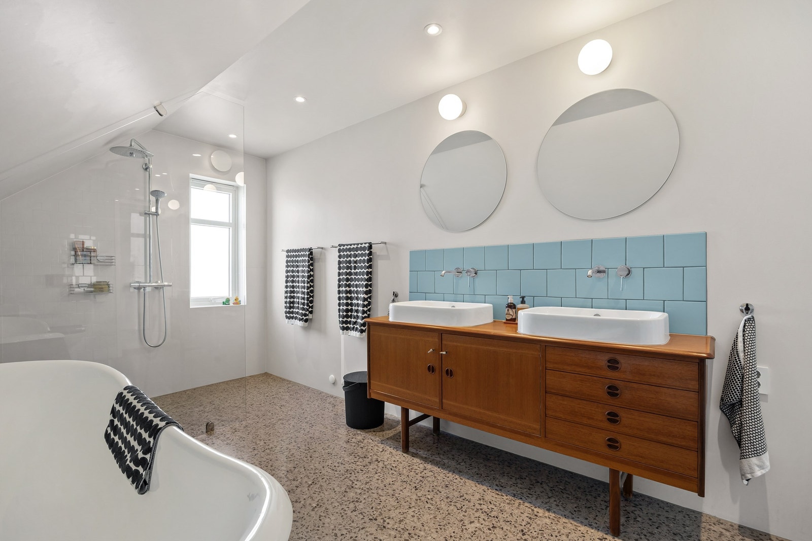 Et romslig og lekkert bad med både dusjnisje og et frittstående badekar av støpejern. Det er gulvvarme og innfelte downlights i taket. Galleribilde