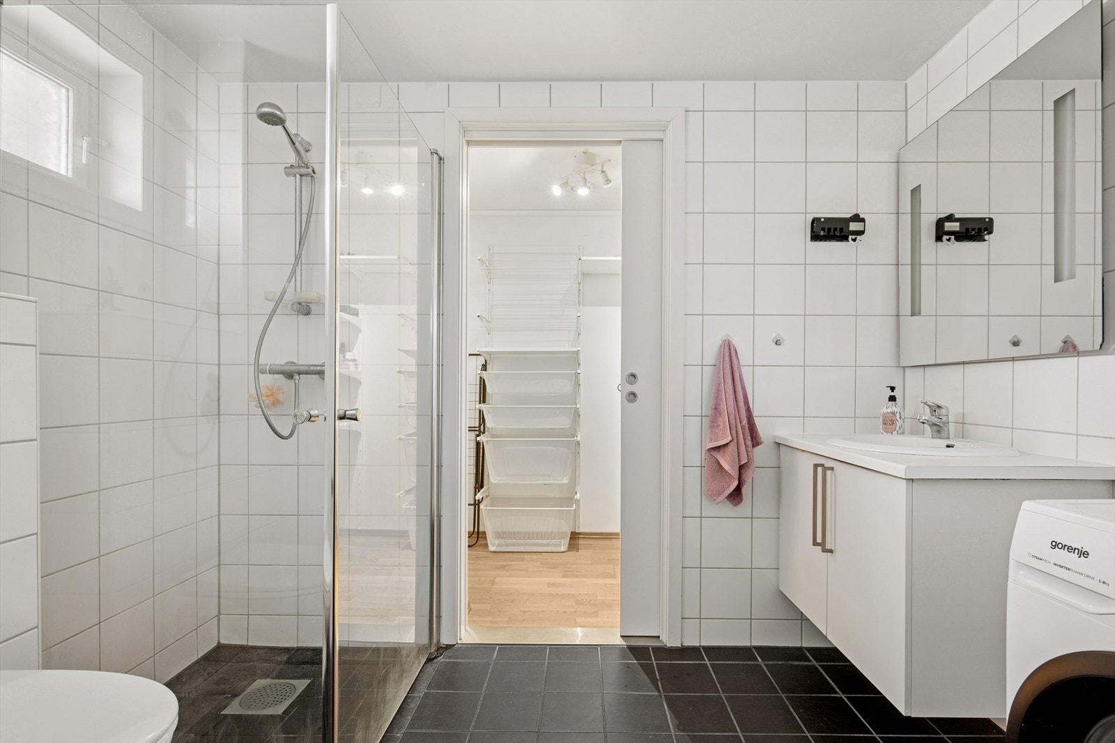 Bad/vaskerom er flislagt med mørke fliser på gulvet og hvite på veggene. Galleribilde