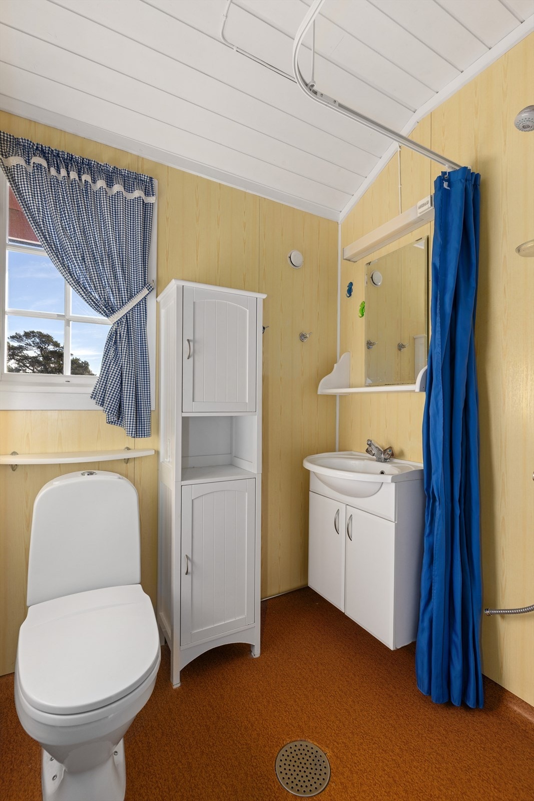 Badet inneholder toalett, håndvask med skap og dusjhjørne. Galleribilde