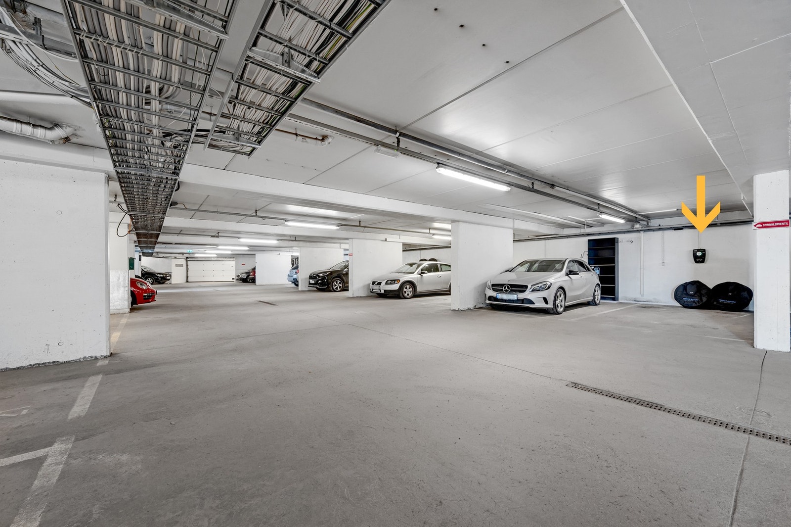 Parkeringsplass med El-bil lader i felles parkeringsetasje. Det er også bod i denne etasjen. Galleribilde