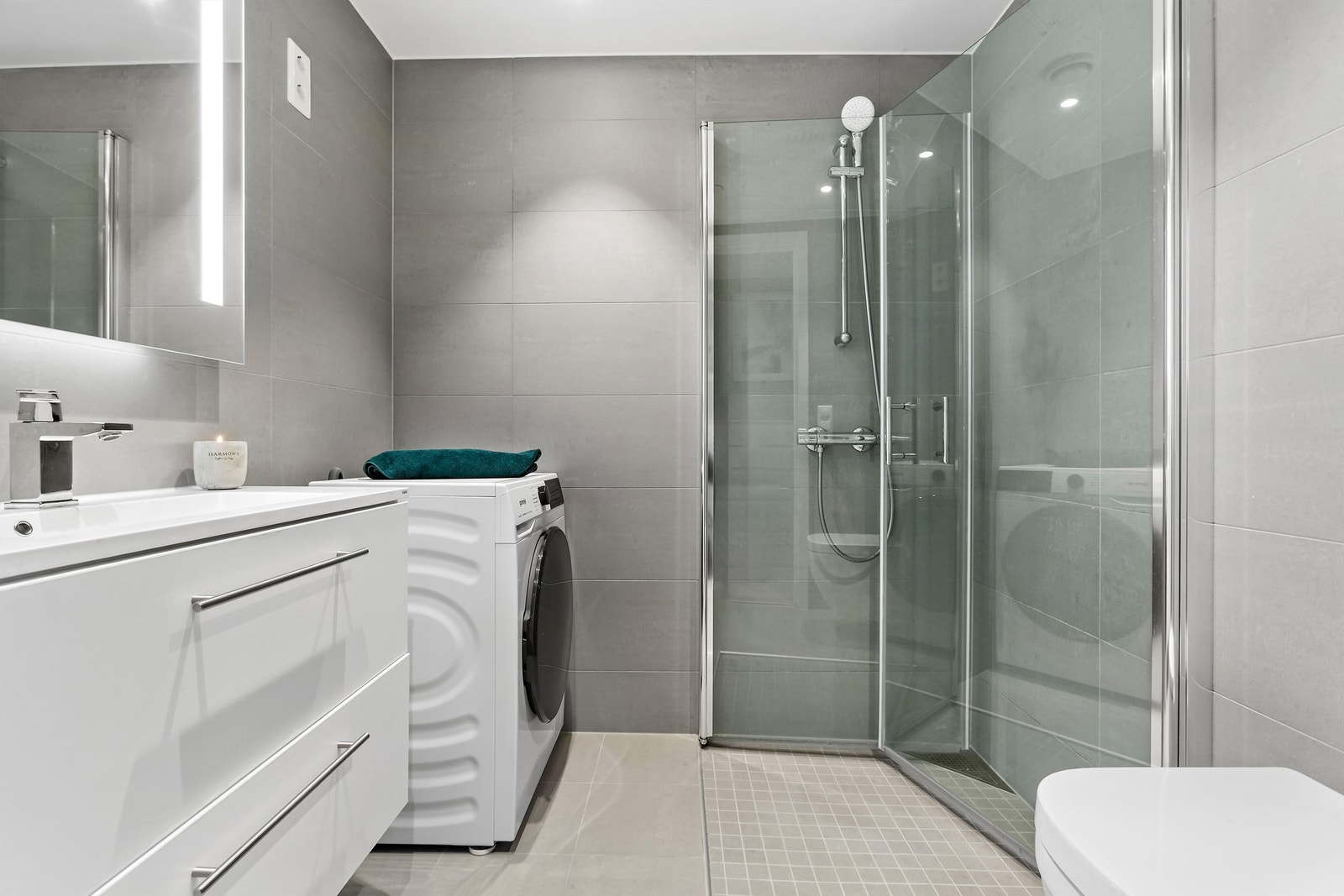 Badet er fra 2021 med flislagte overflater, gulvvarme og et dusjhjørne med innfellbare glassdører. Galleribilde