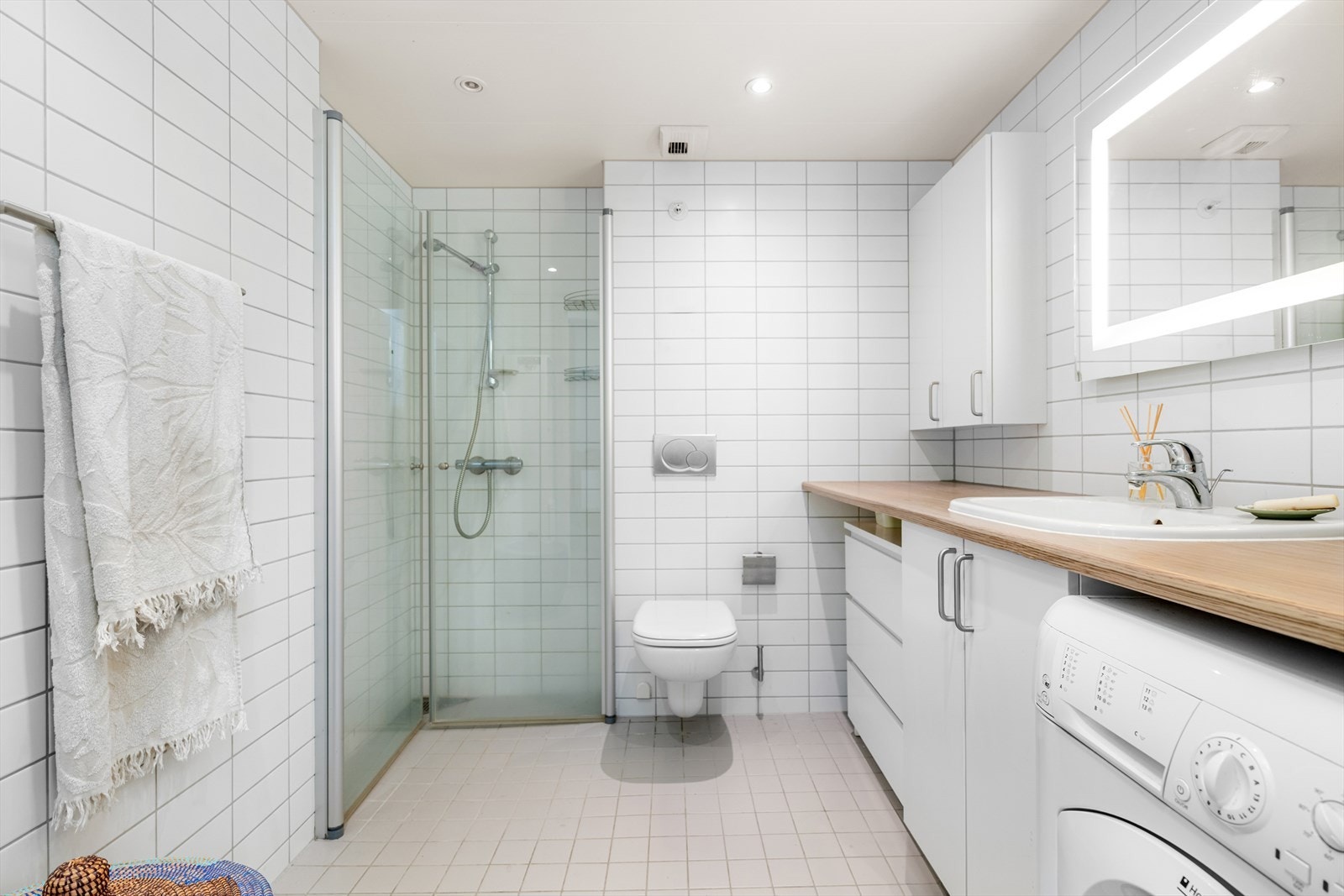 Lyst baderom med fliser på gulv og vegger. Badet er utstyrt med behagelig gulvvarme og stilrene downlights i taket, som gir både komfort og et moderne uttrykk. Galleribilde