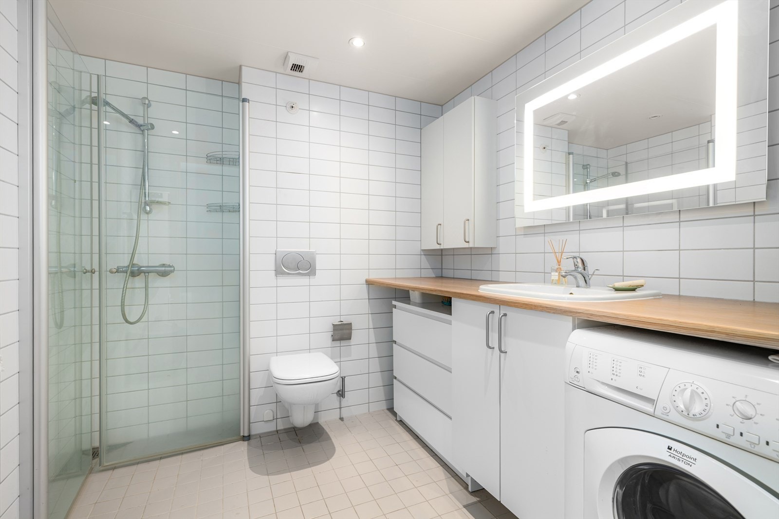 På badet er det servant med servantskap, speil, veggfestet toalett, hjørnedusj med innfellbare glassdører og opplegg for vaskemaskin. Galleribilde