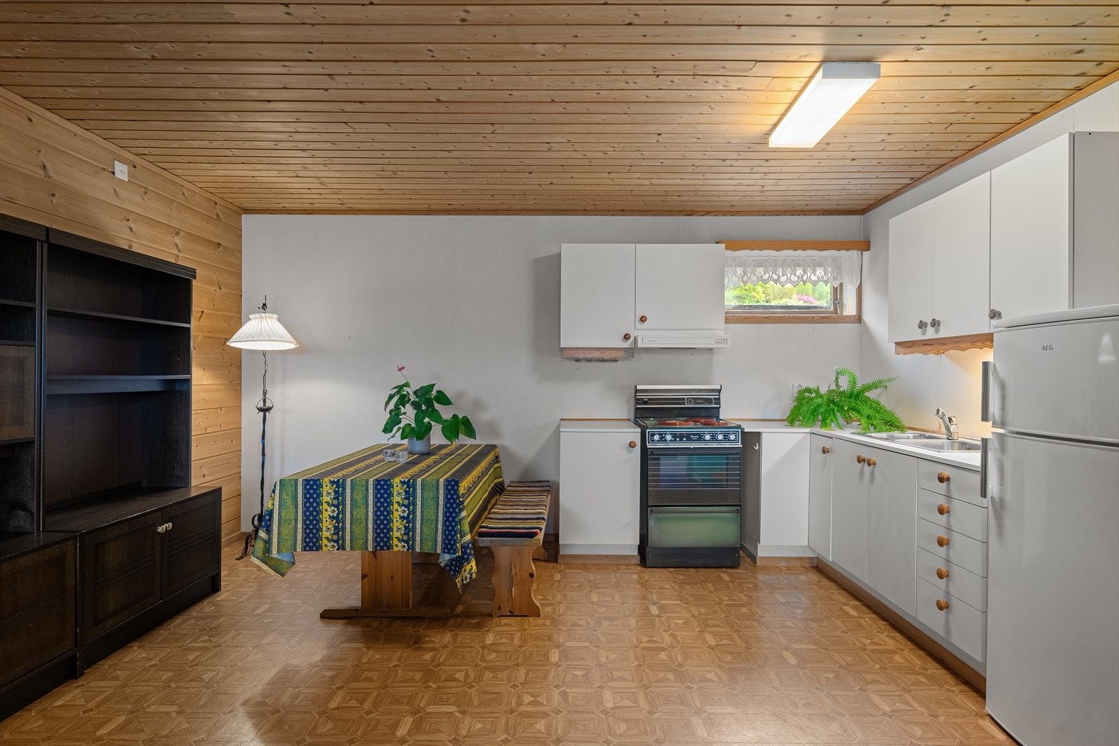 Kjøkkenet er fra byggeår og har belegg på gulv og tapet på vegger. Det er glatte hvite fronter og benkeplaten er av laminat. (den delen hvor bla. bordet står er iht tegning godkjent som bod). Galleribilde