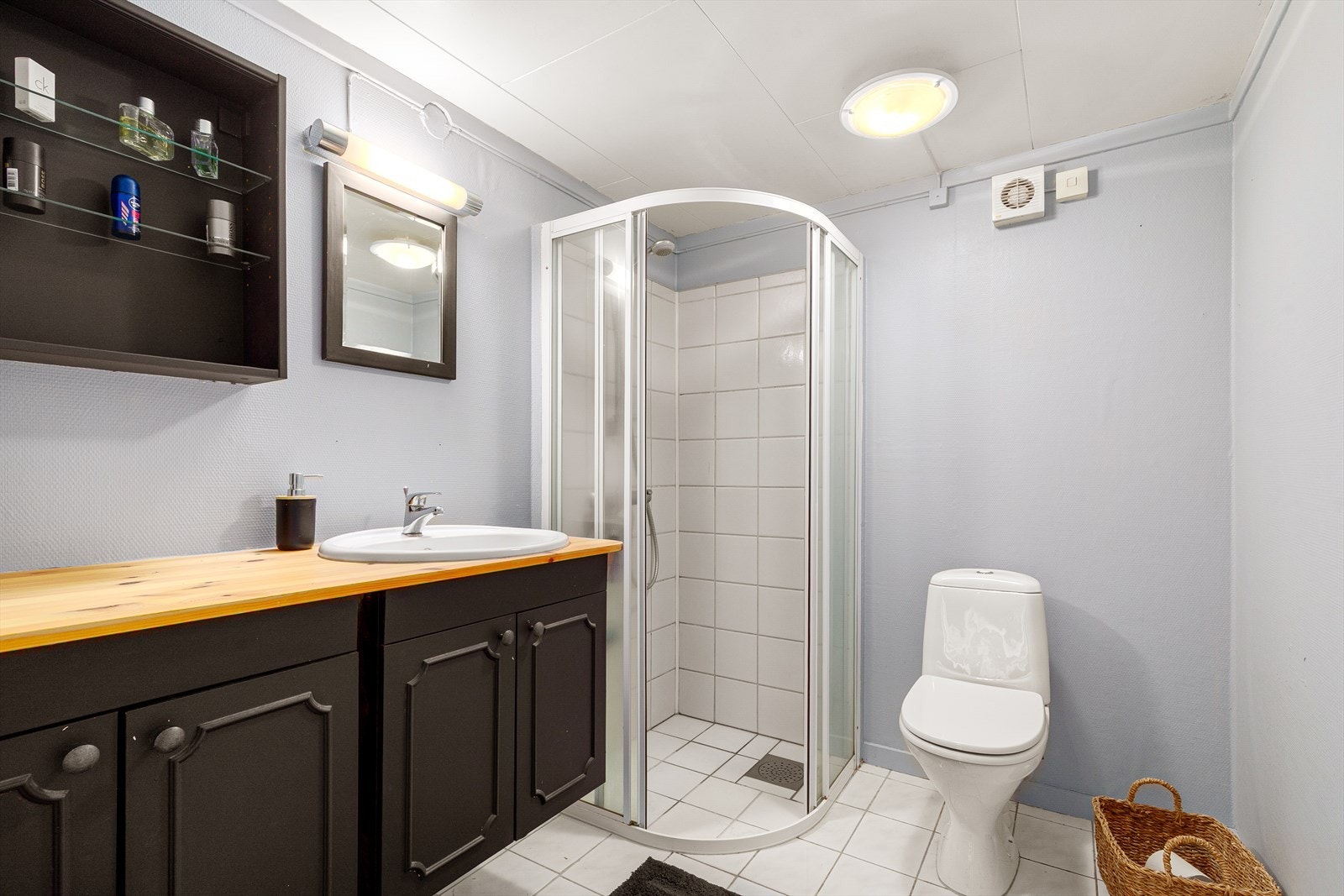 Badet i underetasjen har lyse fliser på gulvet og hvite fliser på veggene i dusjområdet, samt malt strie på de øvrige veggene. Det er varme i gulvet. Deler av badet er byggemeldt som bod. Galleribilde